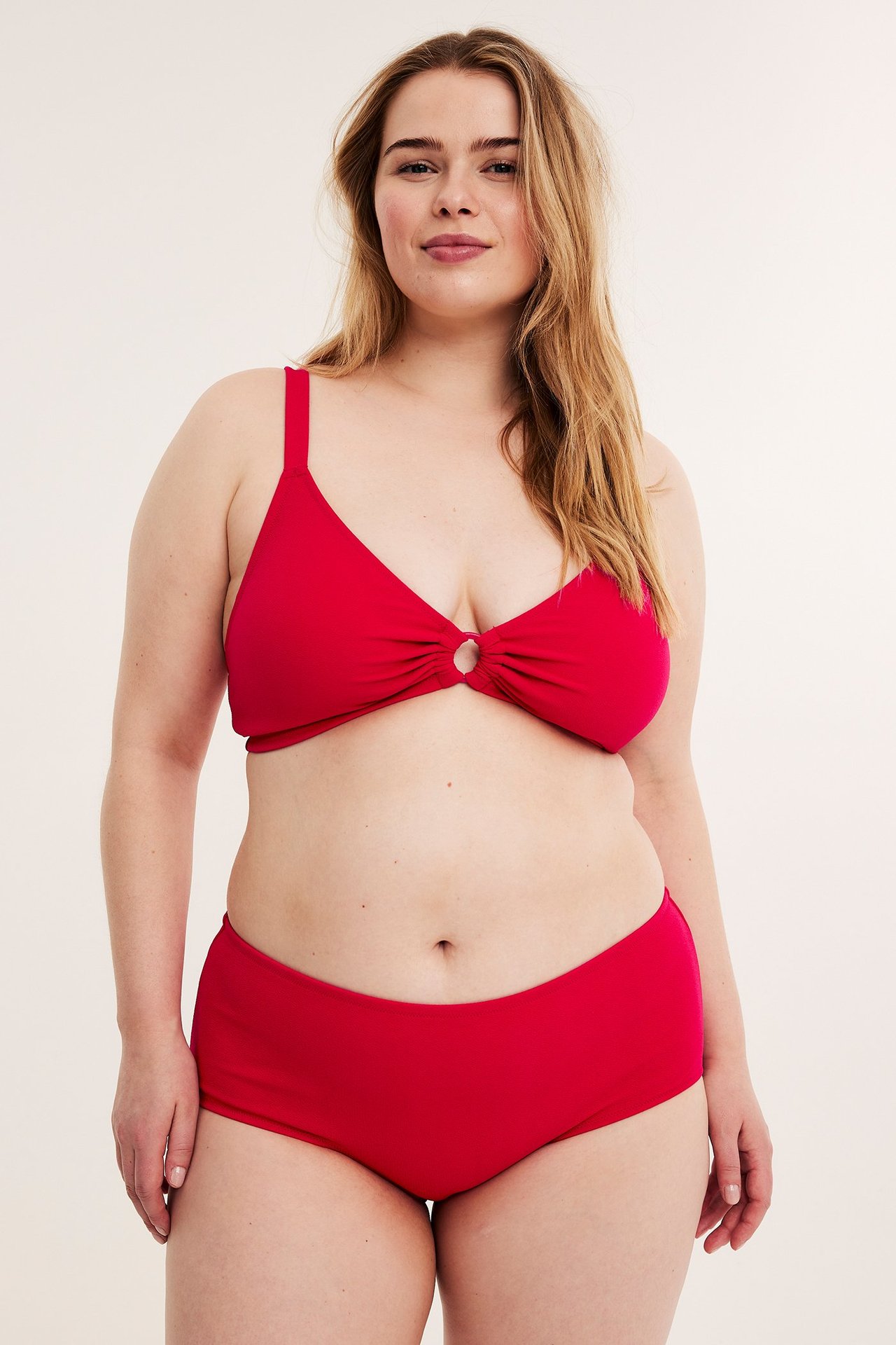 Framifrån, kvinna i röd crepad hög midja hipster bikinitrosa och matchande röd bikinitopp.