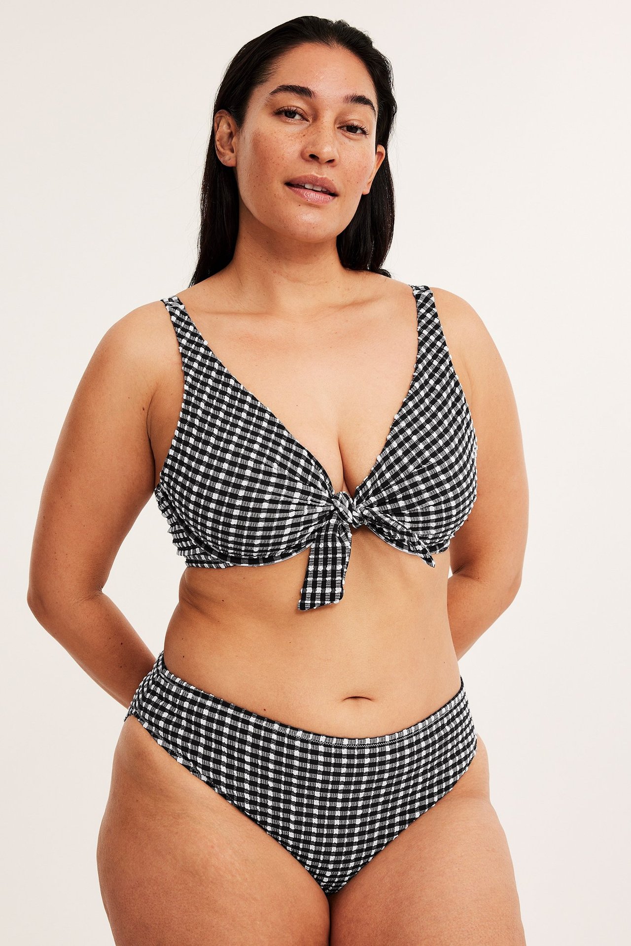 Frontbilde av kvinne i svart-hvitt rutete seersucker-bikini med knytetopp foran.