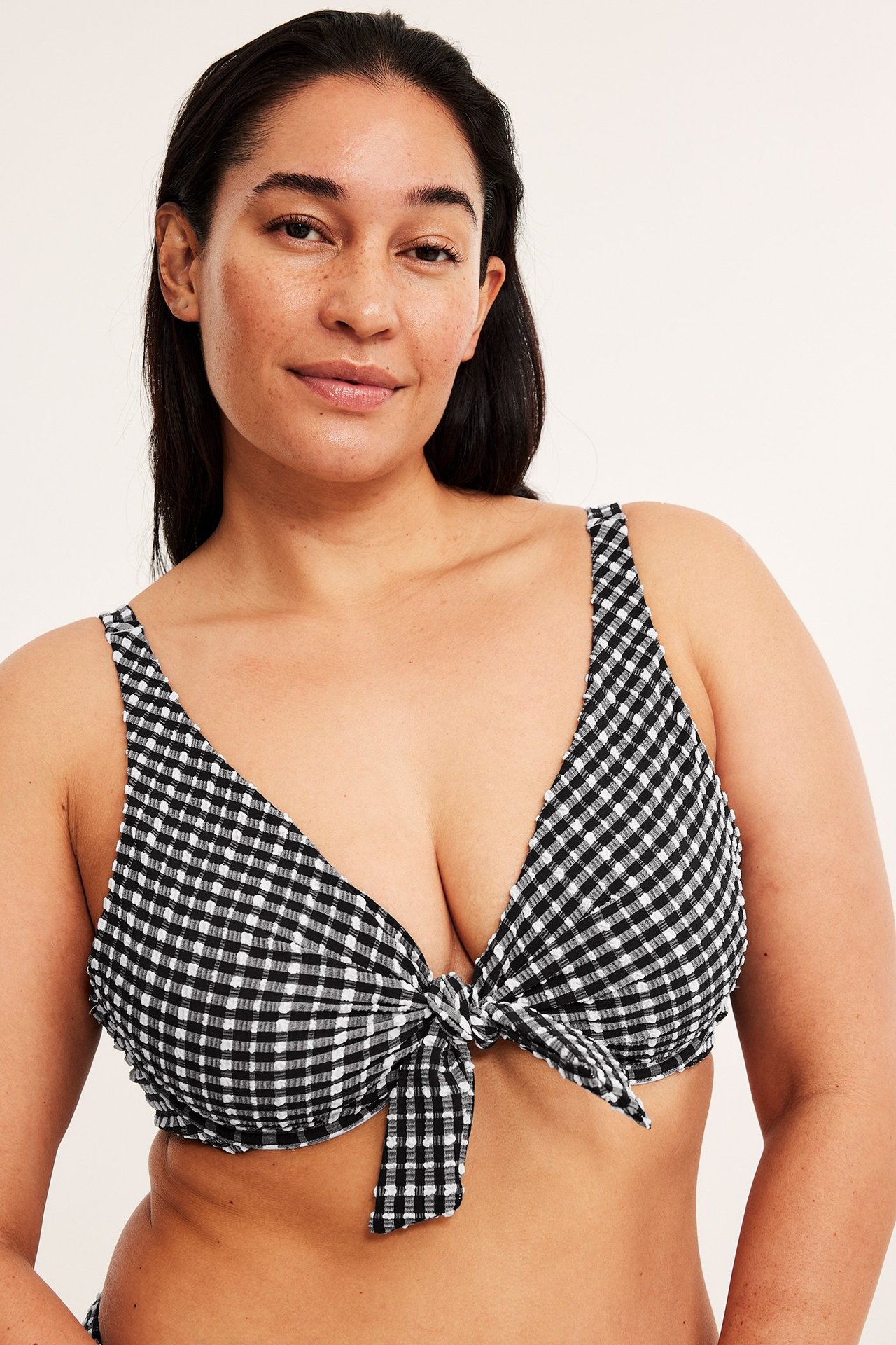 Widok z przodu kobiety w czarno-białym, kratkowanym biustonoszu bikini z seersucker z wiązaniem z przodu.