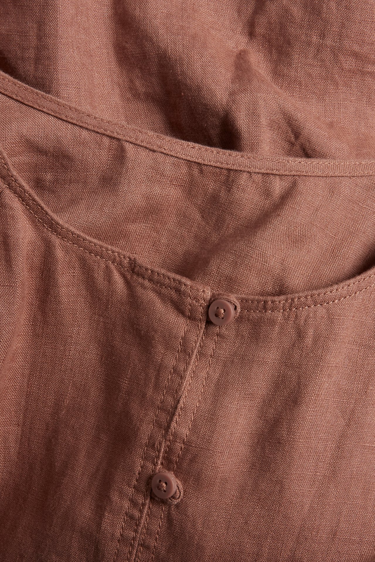 Nærbilde av en brun linbluse med knapper.