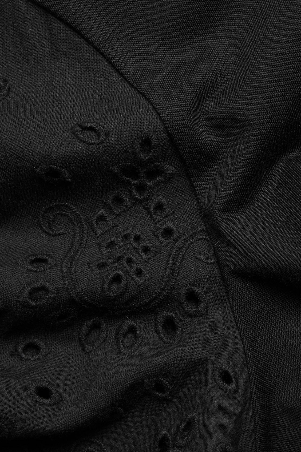 Zbliżenie czarnego bawełnianego T-shirtu z haftem angielskim i misternym haftem.