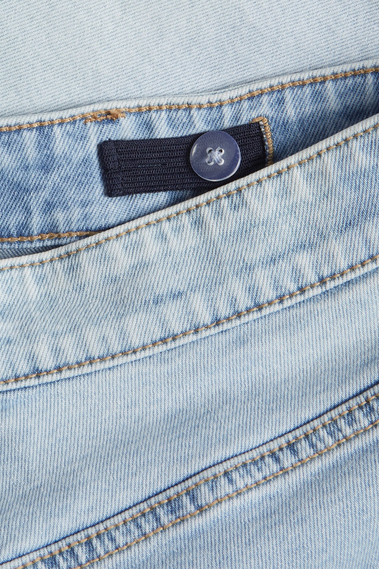 Närbild på barnens ljusa denimjeansshorts med justerbar resår i midjan och blå knapp.