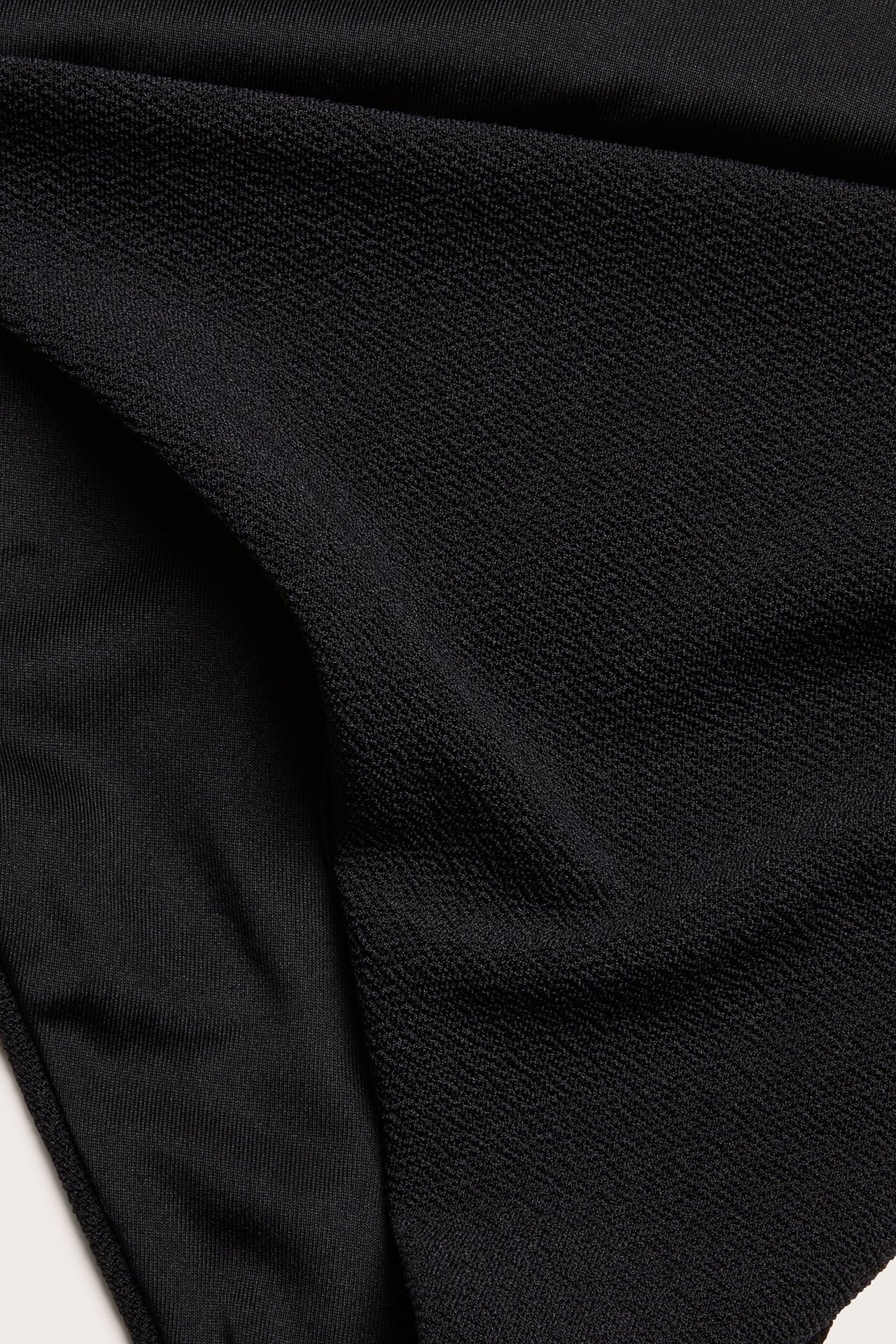 Zbliżenie czarnych, teksturowanych majtek kąpielowych brazilian.