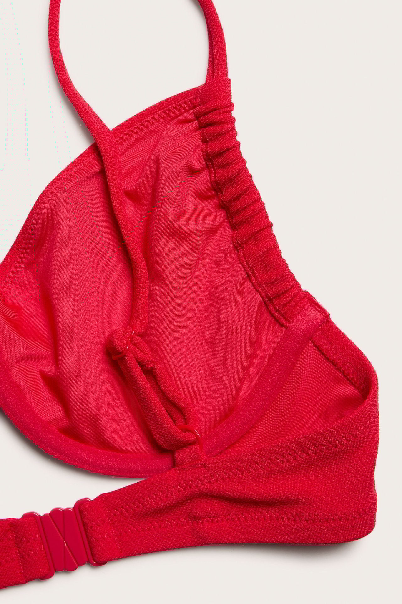 Zbliżenie czerwonego, teksturowanego biustonosza bikini z fiszbinami, regulowanymi ramiączkami i zapięciem z tyłu.