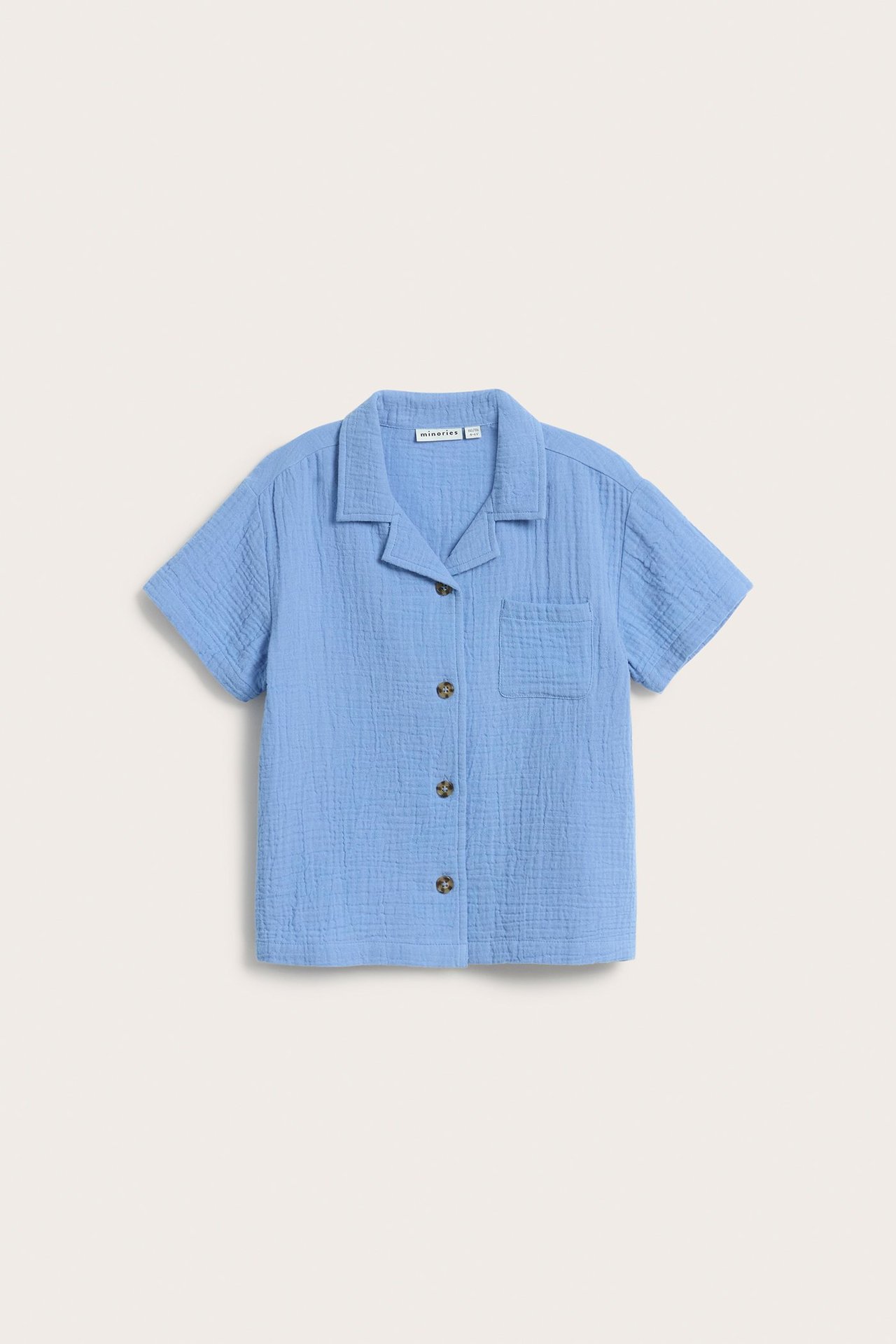 Widok z przodu: jasnoniebieska koszula z krótkim rękawem z muślinu, z kołnierzykiem, guzikami i kieszenią.