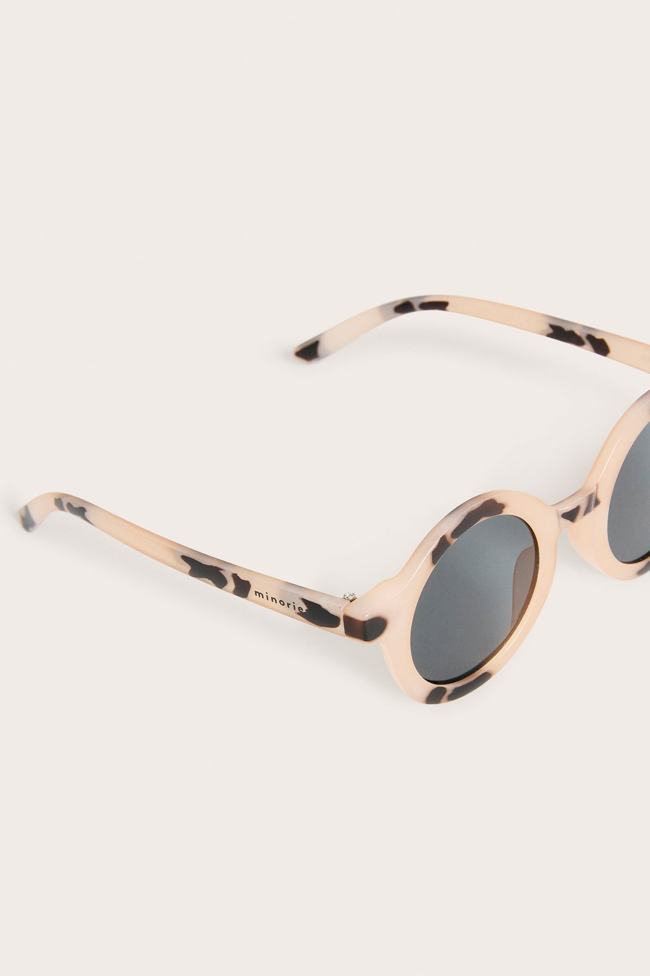 Zbliżenie beżowych, wzorzystych, owalnych okularów przeciwsłonecznych z tworzywa sztucznego z ciemnymi soczewkami.