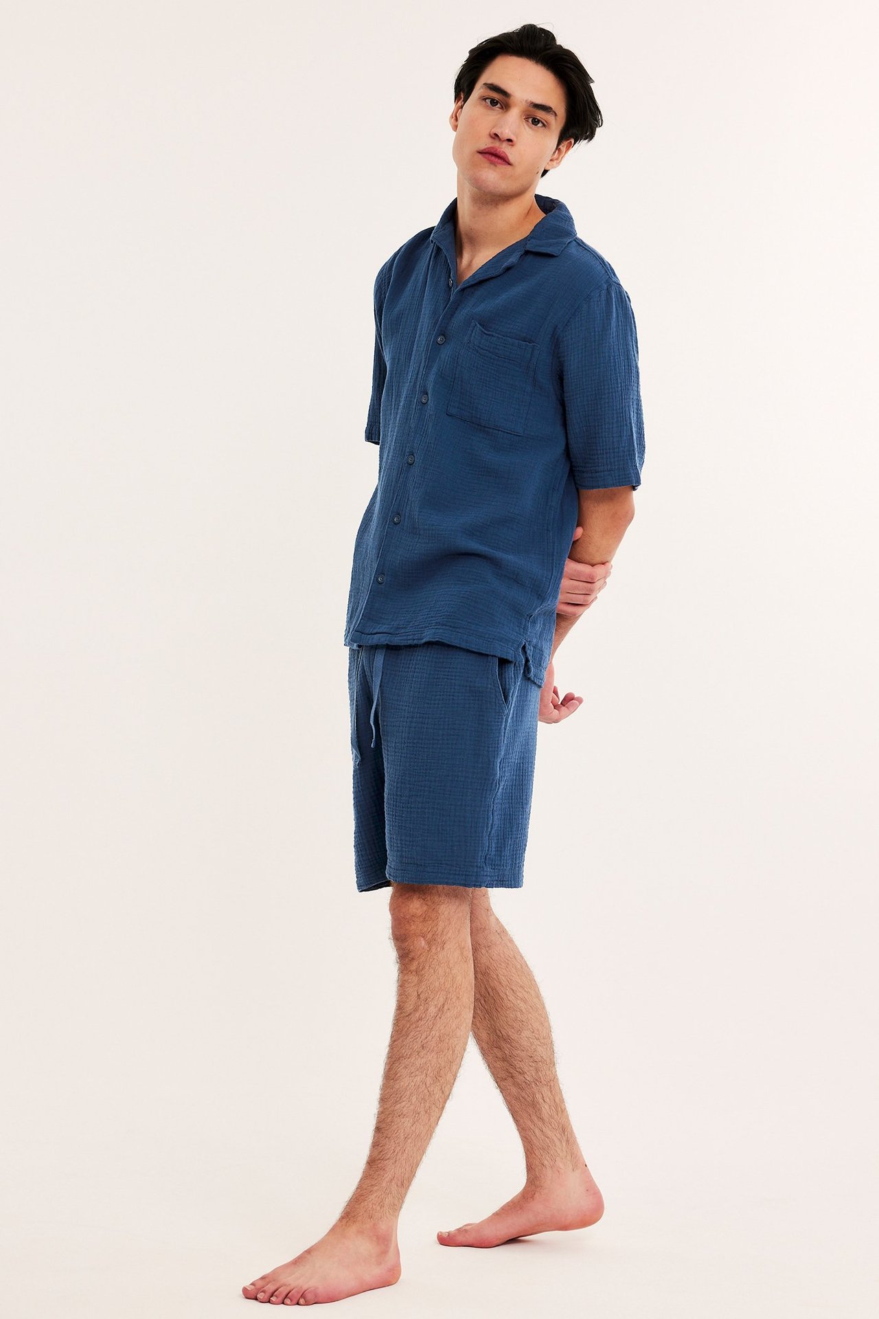 Sivukuva miehestä yllään tummansiniset puuvillakreppi pyjamashortsit kiristysnyörillä ja yhteensopiva lyhythihainen paita.