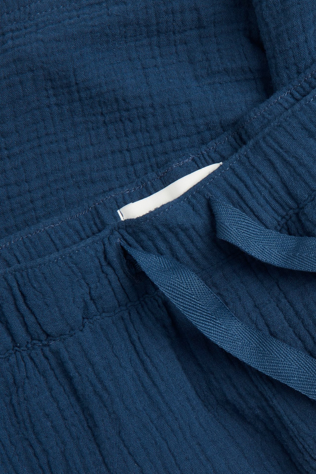 Zbliżenie na granatowe męskie szorty piżamowe z bawełnianej krepy, z elastycznym pasem i sznurkiem.