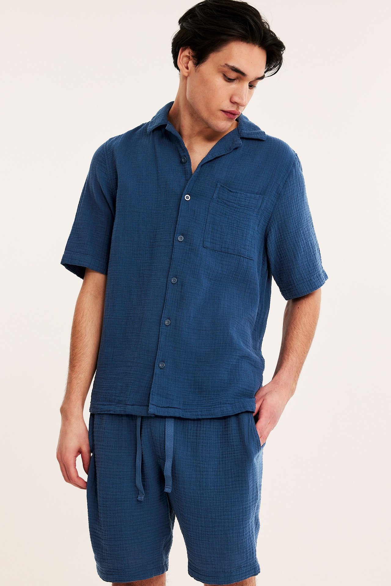 Widok z przodu mężczyzny w granatowych szortach piżamowych z krepy bawełnianej i pasującej koszuli.