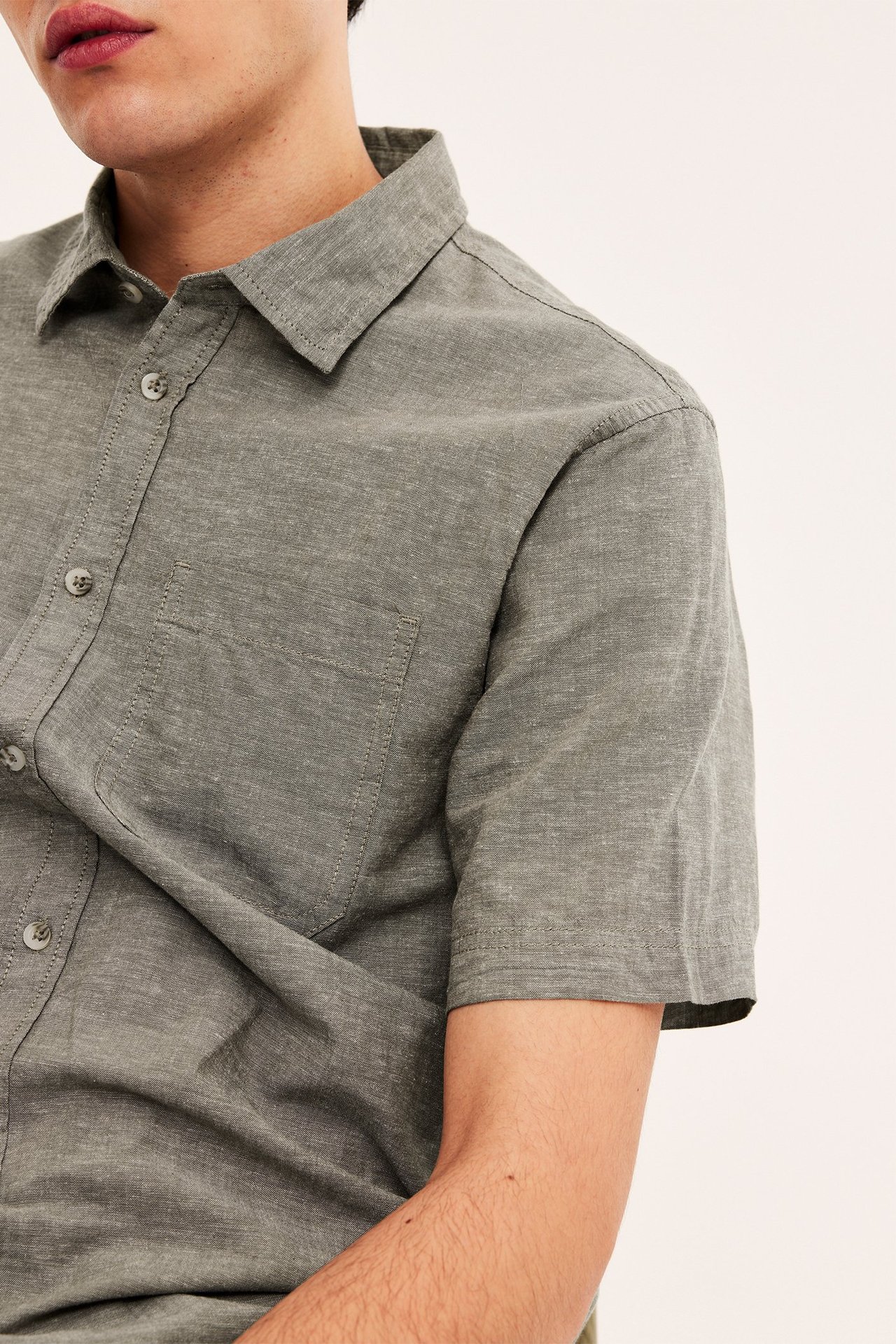 Nærbilde av en mann i en grønn kortermet linskjorte med krage og brystlomme.