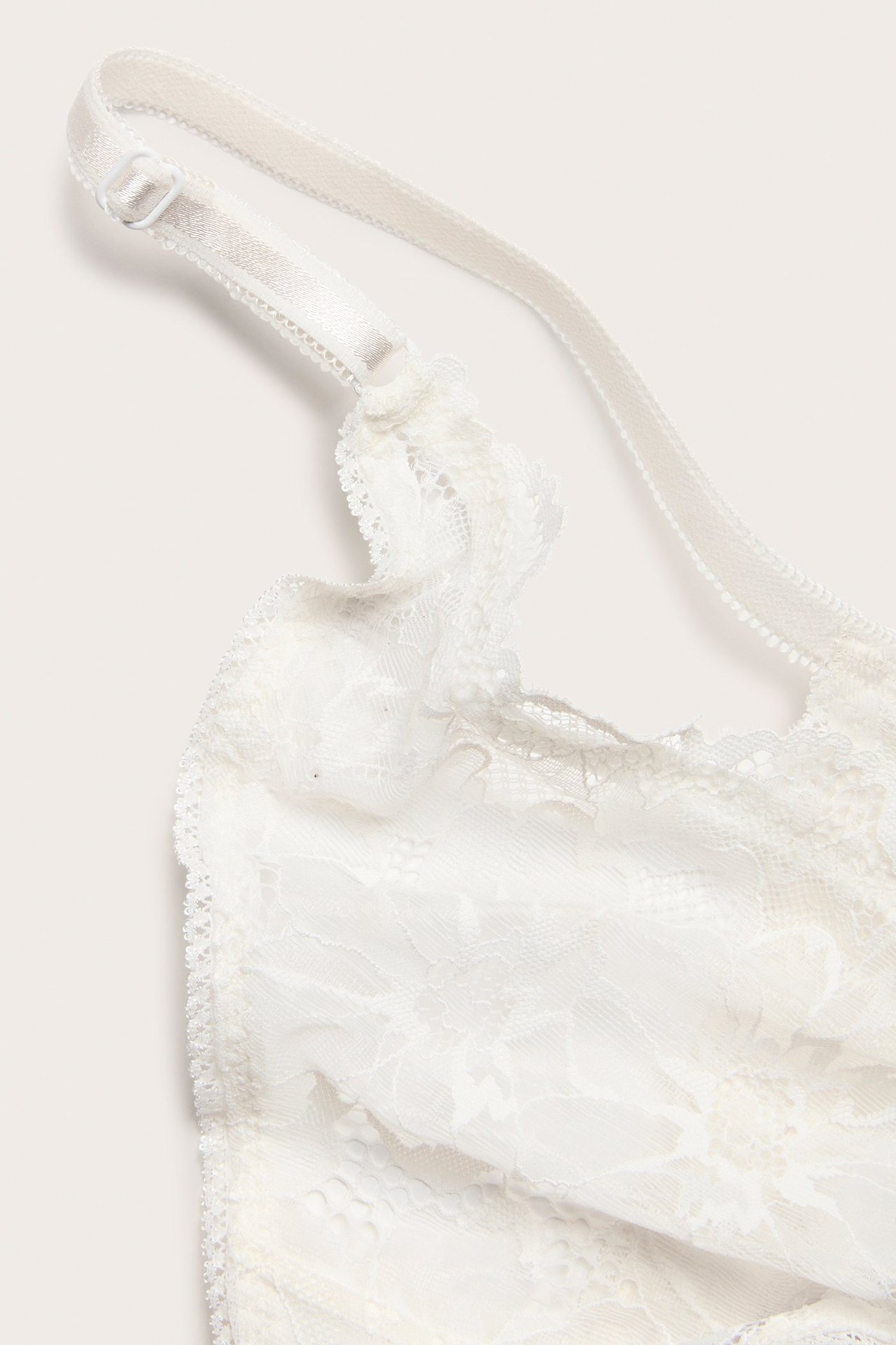 Zbliżenie białych koronkowych stringów z regulowanym paskiem.