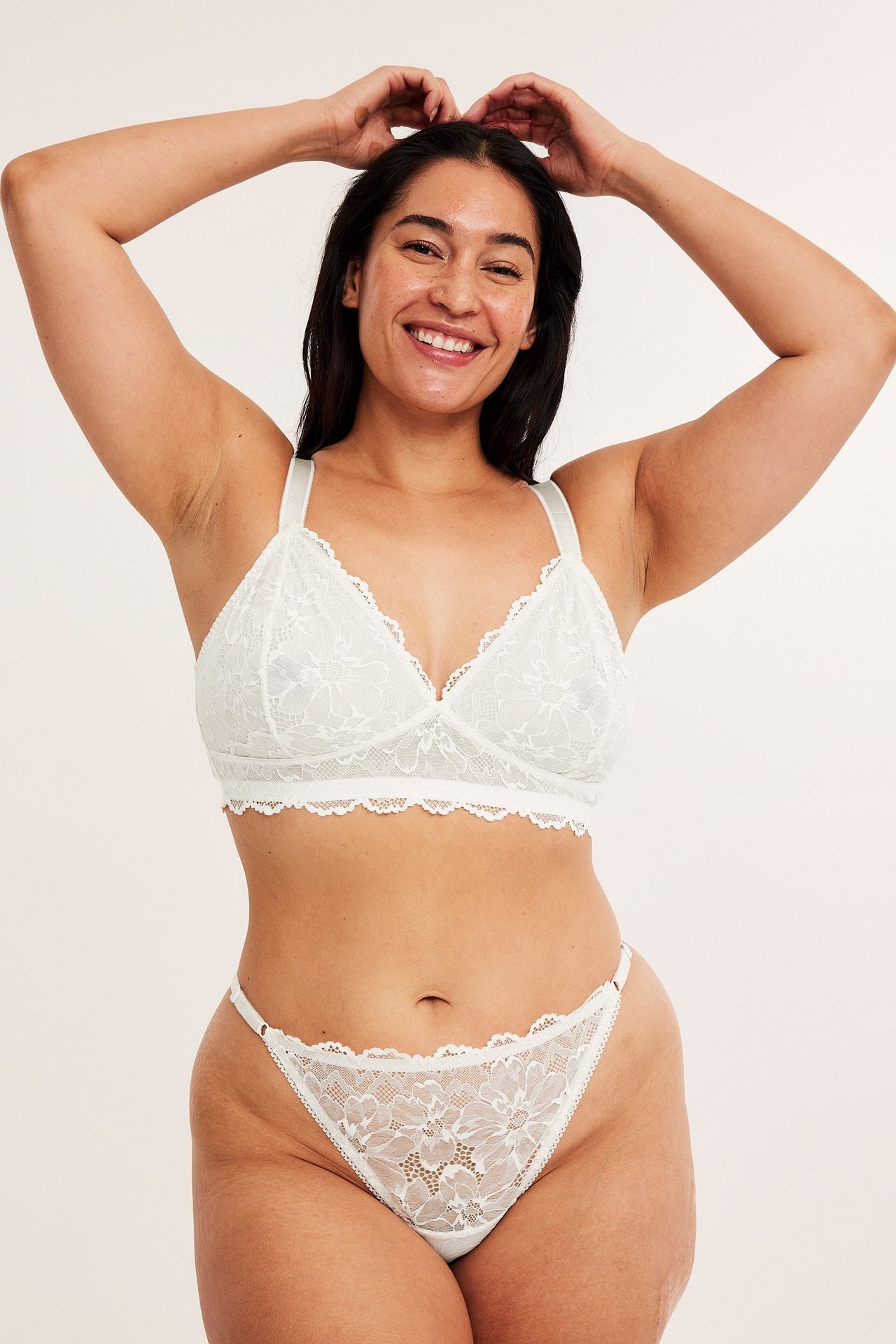 Forfra, kvinne i hvit blondestringtruse med justerbare stropper og matchende blondebralette.