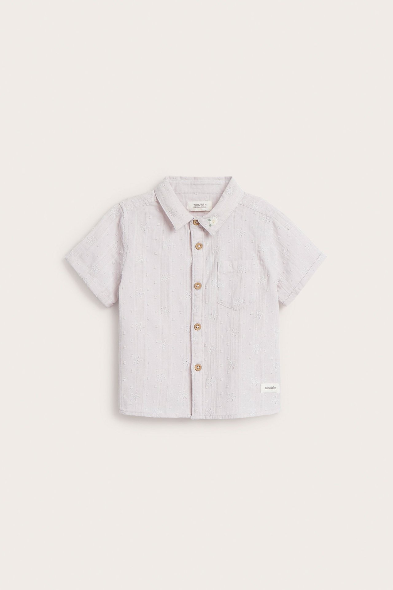 Widok z przodu: Dziecięca jasnofioletowa koszula bawełniana z krótkim rękawem, haftem, kołnierzykiem, kieszenią i guzikami.