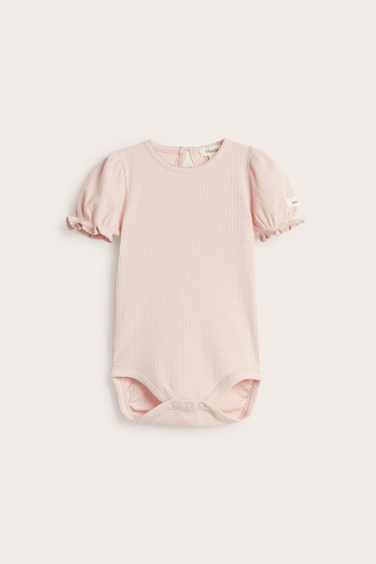 Framifrån sett, en kortärmad body till barn med knäppning i grenen och liten volang i ärmslutet.