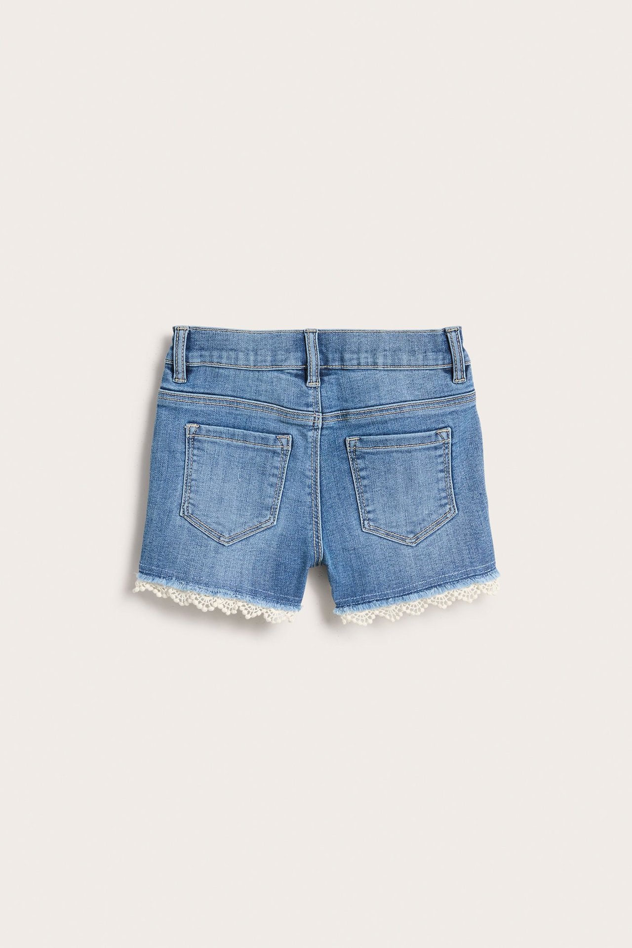 Widok z tyłu jasnoniebieskich dziecięcych szortów jeansowych stretch z dwiema kieszeniami i białą koronką.