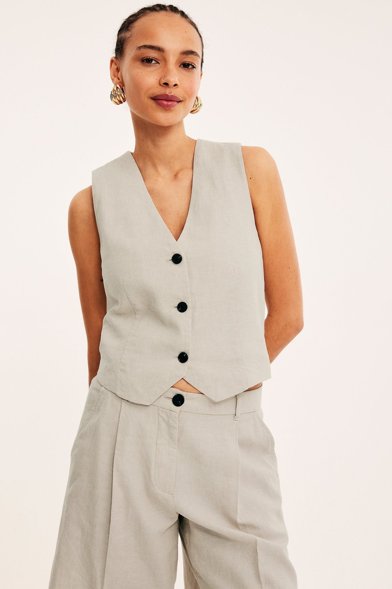 Widok z przodu: kobieta w ecru melanżowej kamizelce z lnu z czarnymi guzikami i pasujących szerokich spodniach.