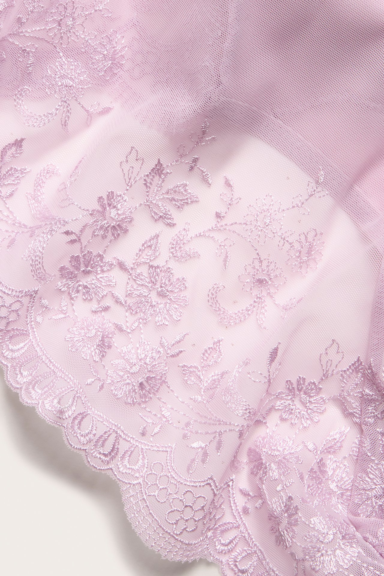 Zbliżenie liliowego materiału siateczkowego z delikatnym haftem kwiatowym, część fig brazylijskich.