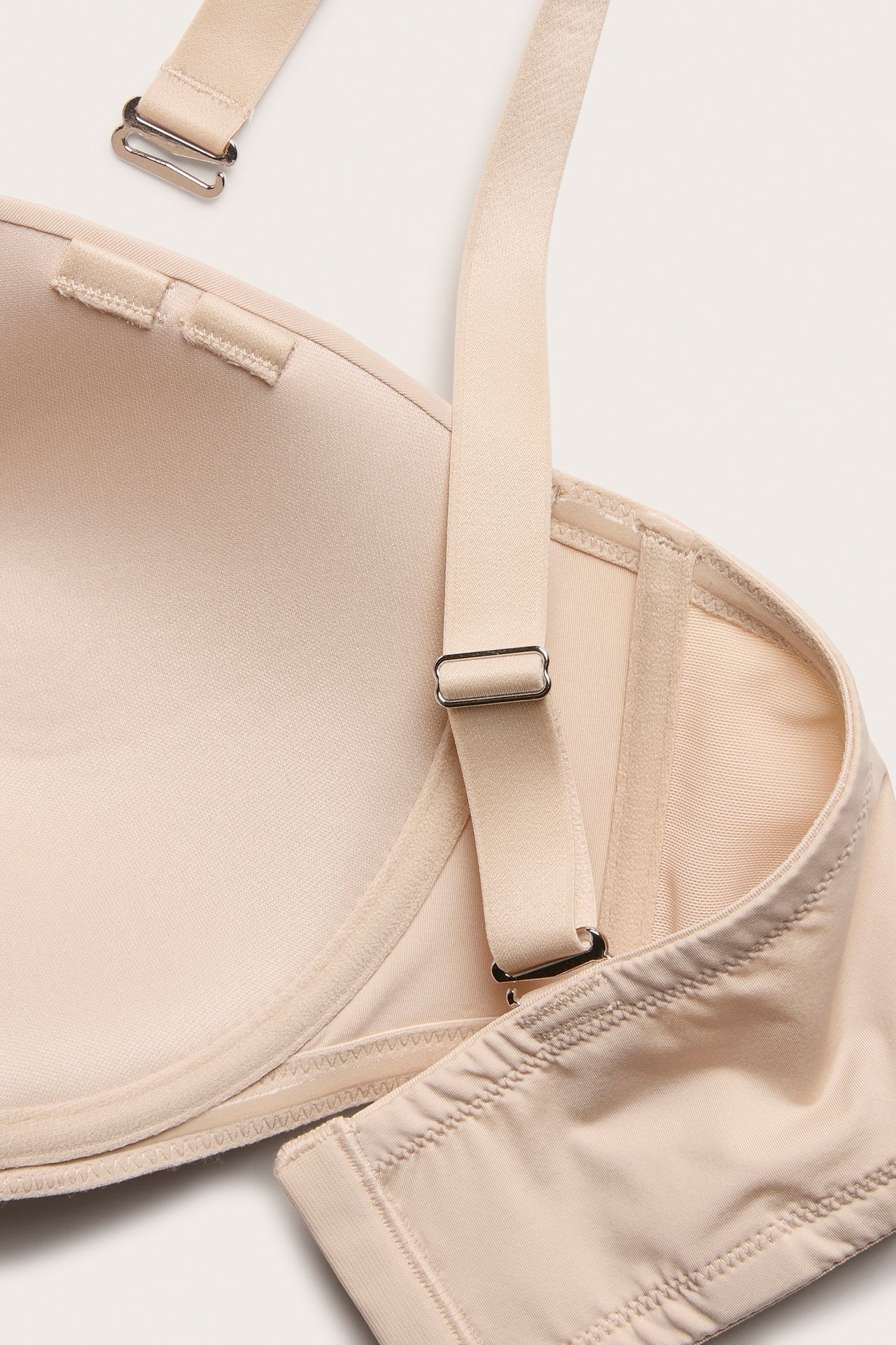 Zbliżenie beżowego biustonosza balconette z mikrofibry z regulowanymi, odpinanymi ramiączkami.