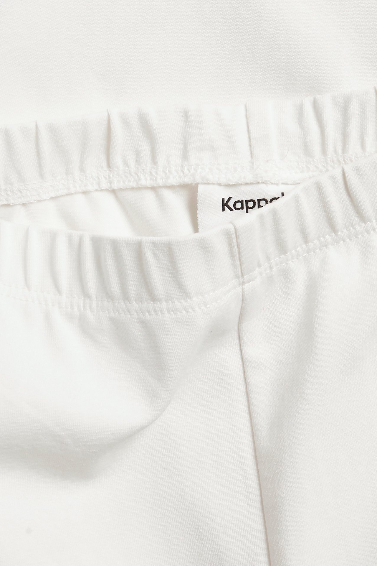 Närbild av offwhite caprileggings i bomullsblandning med resår i midjan.