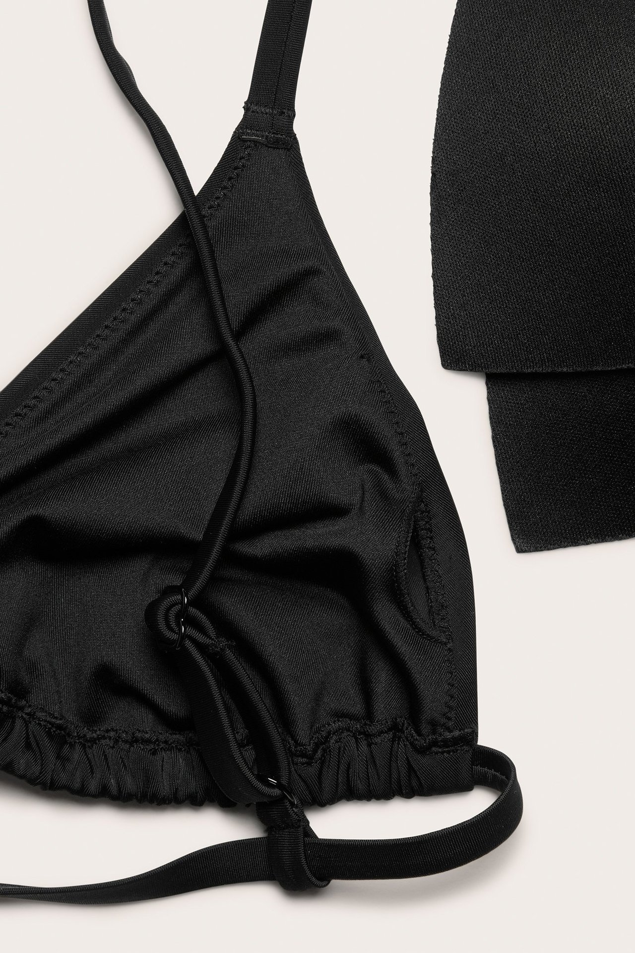 Zbliżenie czarnego biustonosza bikini typu trójkąt z wiązanymi ramiączkami i wyjmowanymi wkładkami.