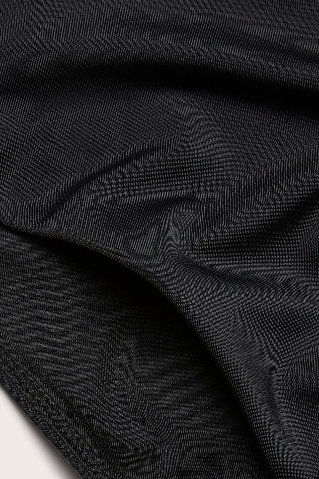 Zbliżenie czarnych, wysokich majtek kąpielowych z subtelną prążkowaną fakturą i widocznymi szwami.