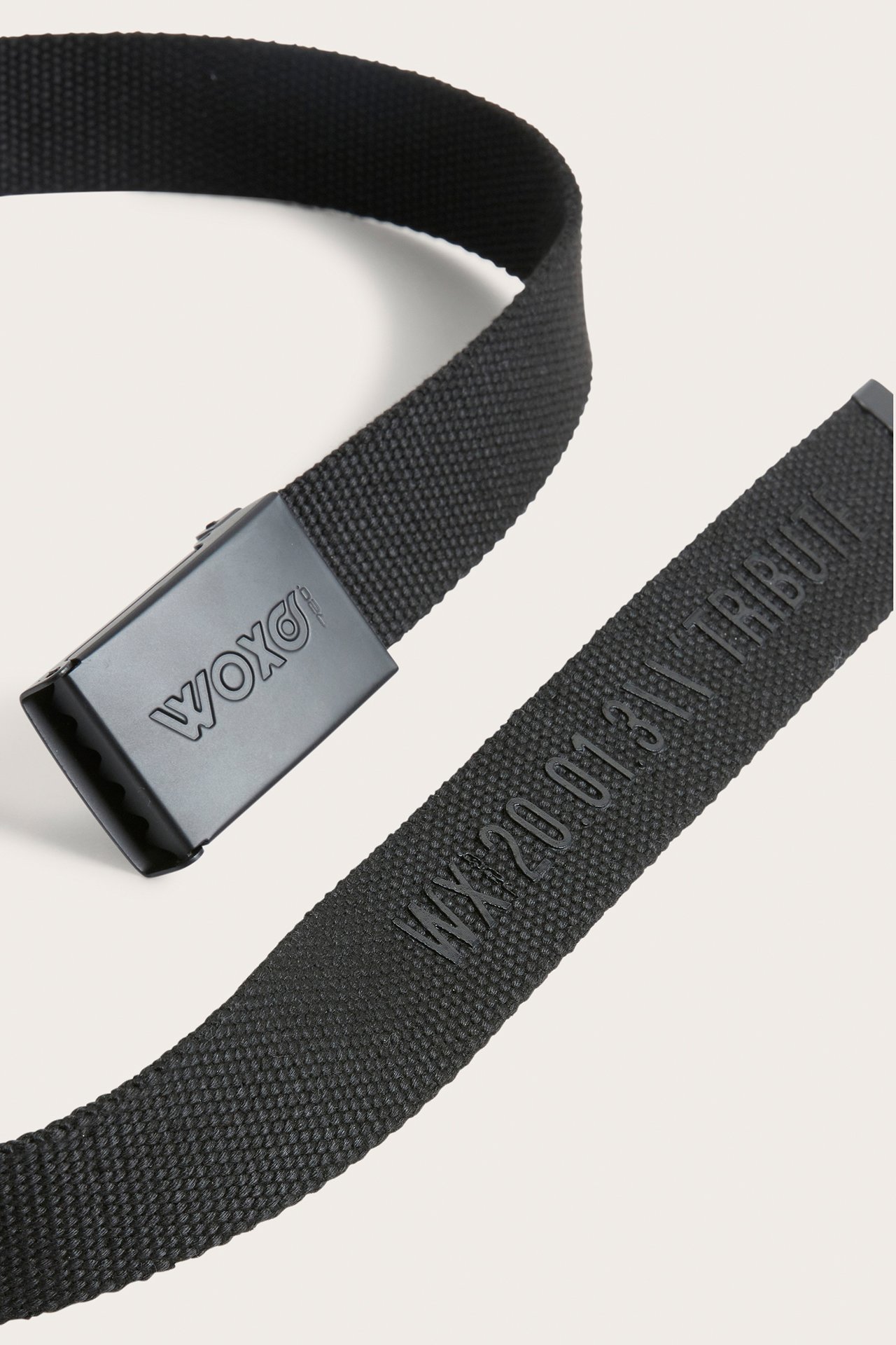 Närbild av ett svart vävt polyesterbälte med svart metallspänne med WOXO och präglad text.