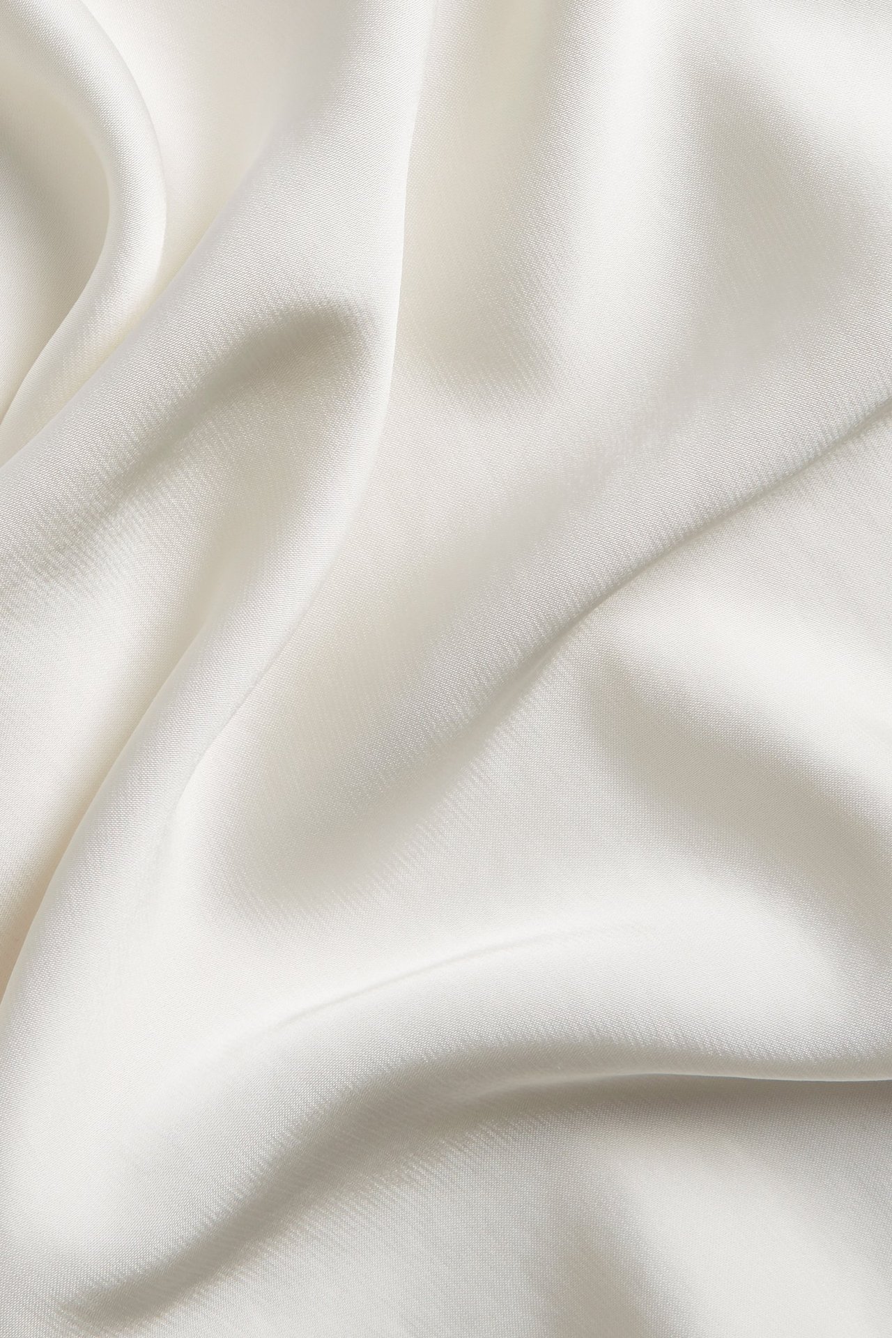 Zbliżenie na ecru poliestrową tkaninę satynową z miękkimi fałdami.