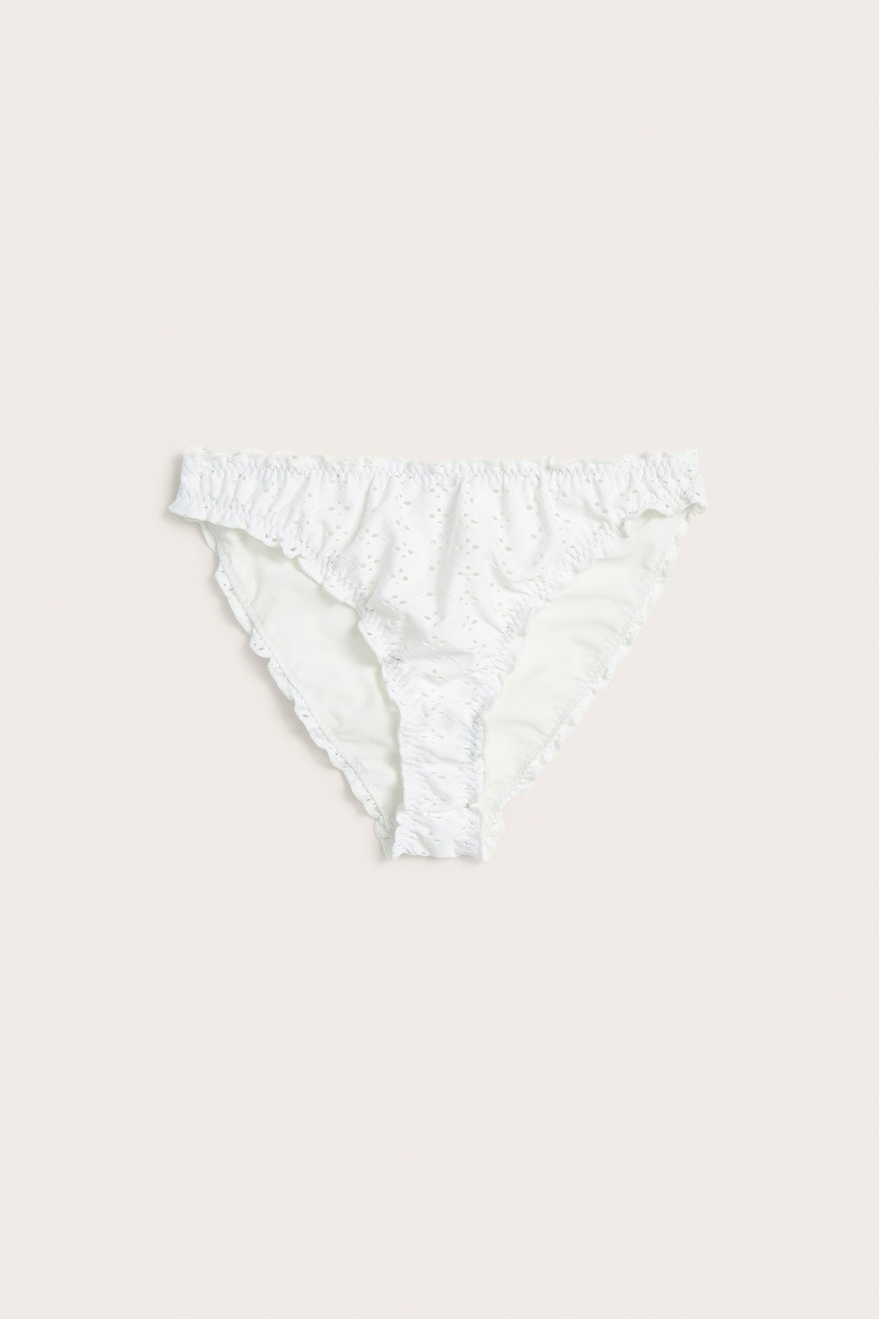 Widok z przodu off-white, żakardowych majtek kąpielowych brazilian z falbankami i średnim stanem.
