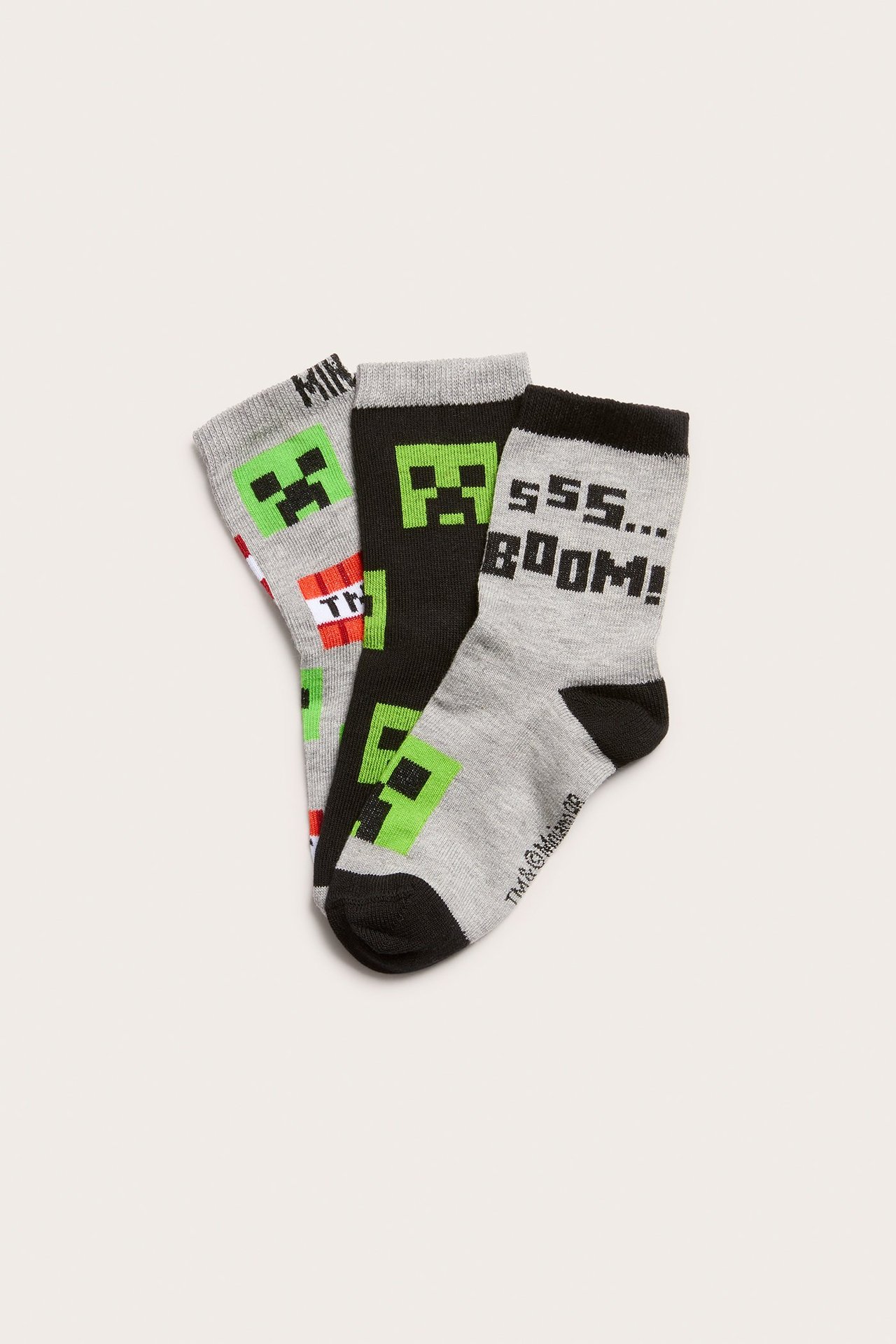 Widok z góry na trzy dziecięce skarpety Minecraft: szare, czarne i szare melanżowe z motywami Minecraft.