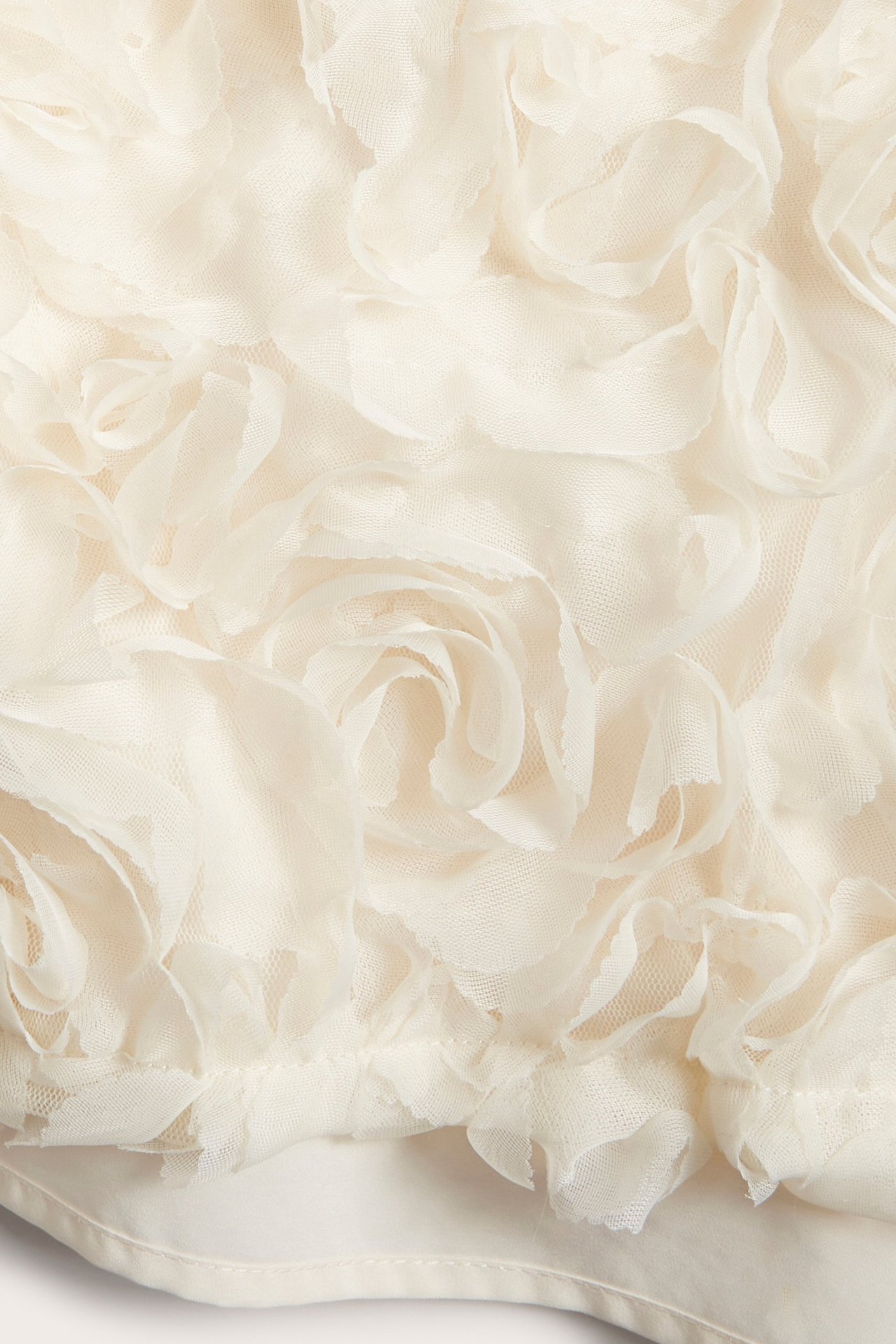 Zbliżenie na ecru siateczkową tkaninę sukienki z efektem róż 3D.
