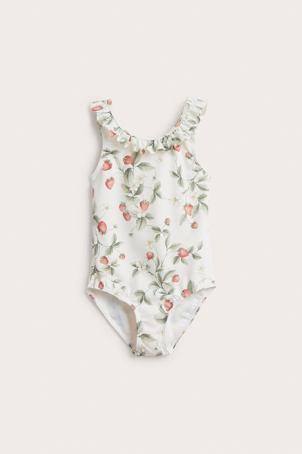 Edestä kuvattu luonnonvalkoinen lasten uimapuku mansikkakuviolla ja röyhelöllä pääntiessä.