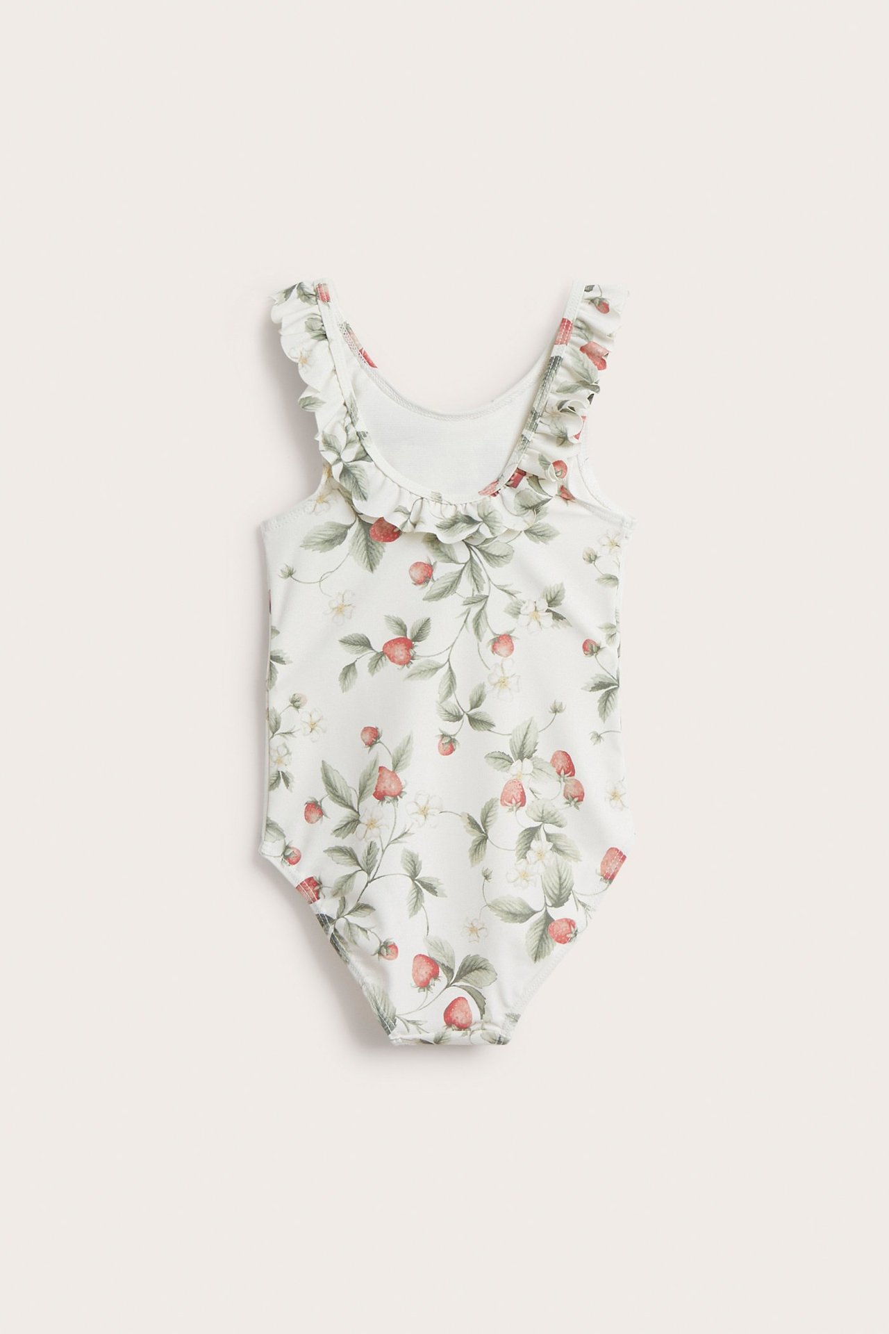 Edestä näkymä luonnonvalkoisesta lasten uimapuvusta, jossa mansikkakuvio ja röyhelökaulus.