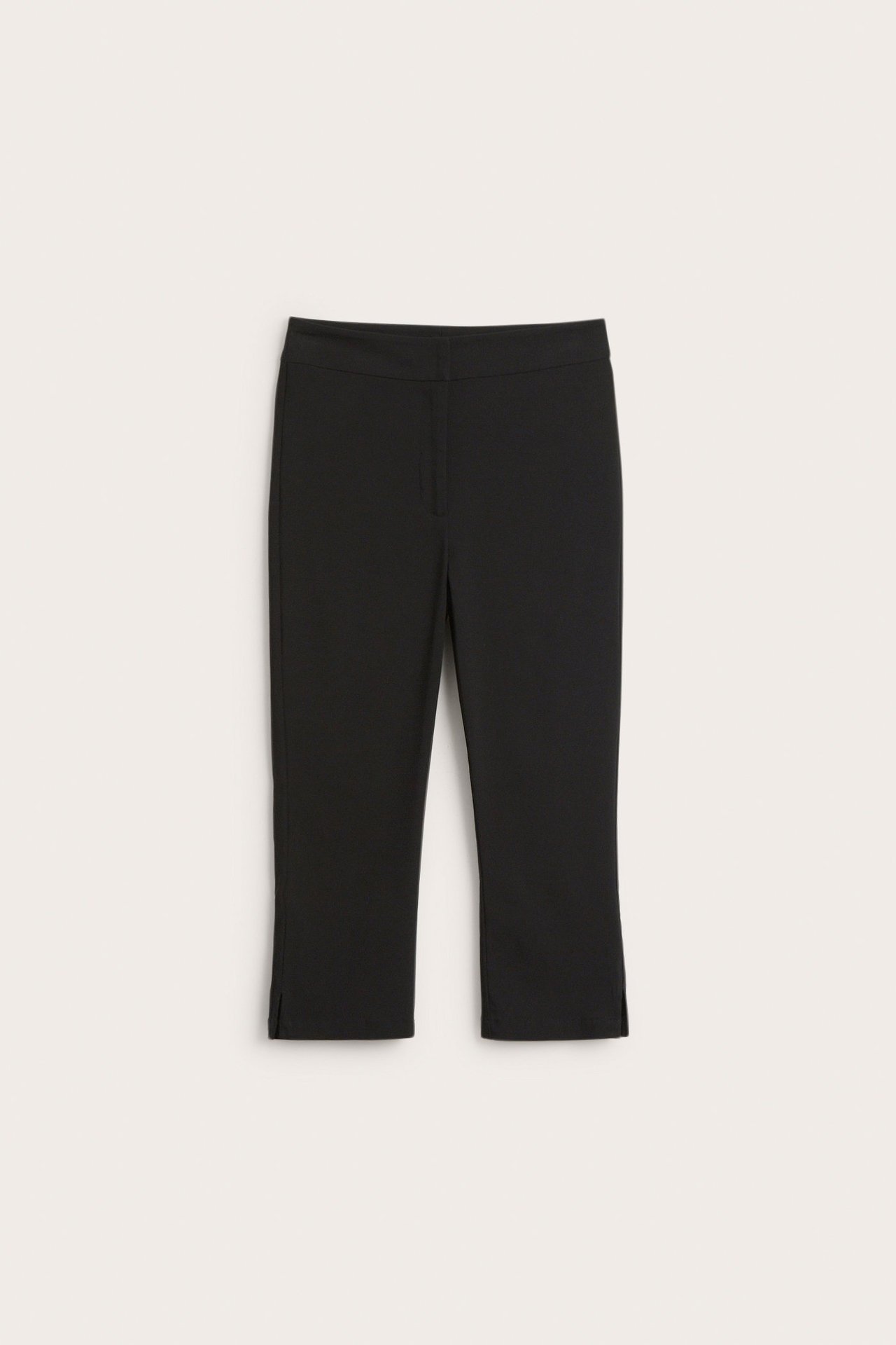 Edestä näkymä mustista bengaliini caprihousuista, joissa pienet halkiot helmassa.