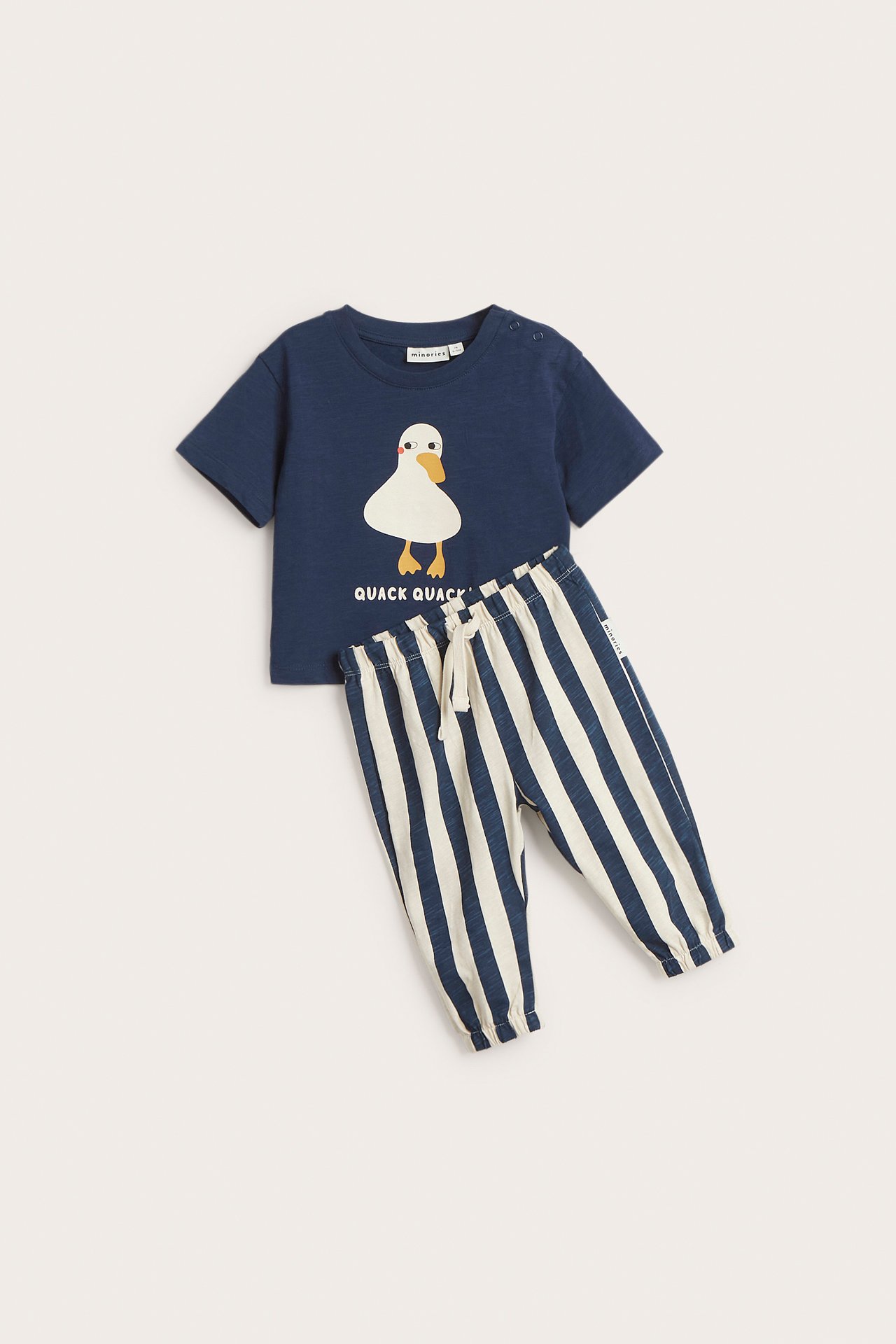 Widok z przodu: Zestaw niemowlęcy: granatowy T-shirt z nadrukiem kaczki i paski spodnie dresowe ze sznurkiem.