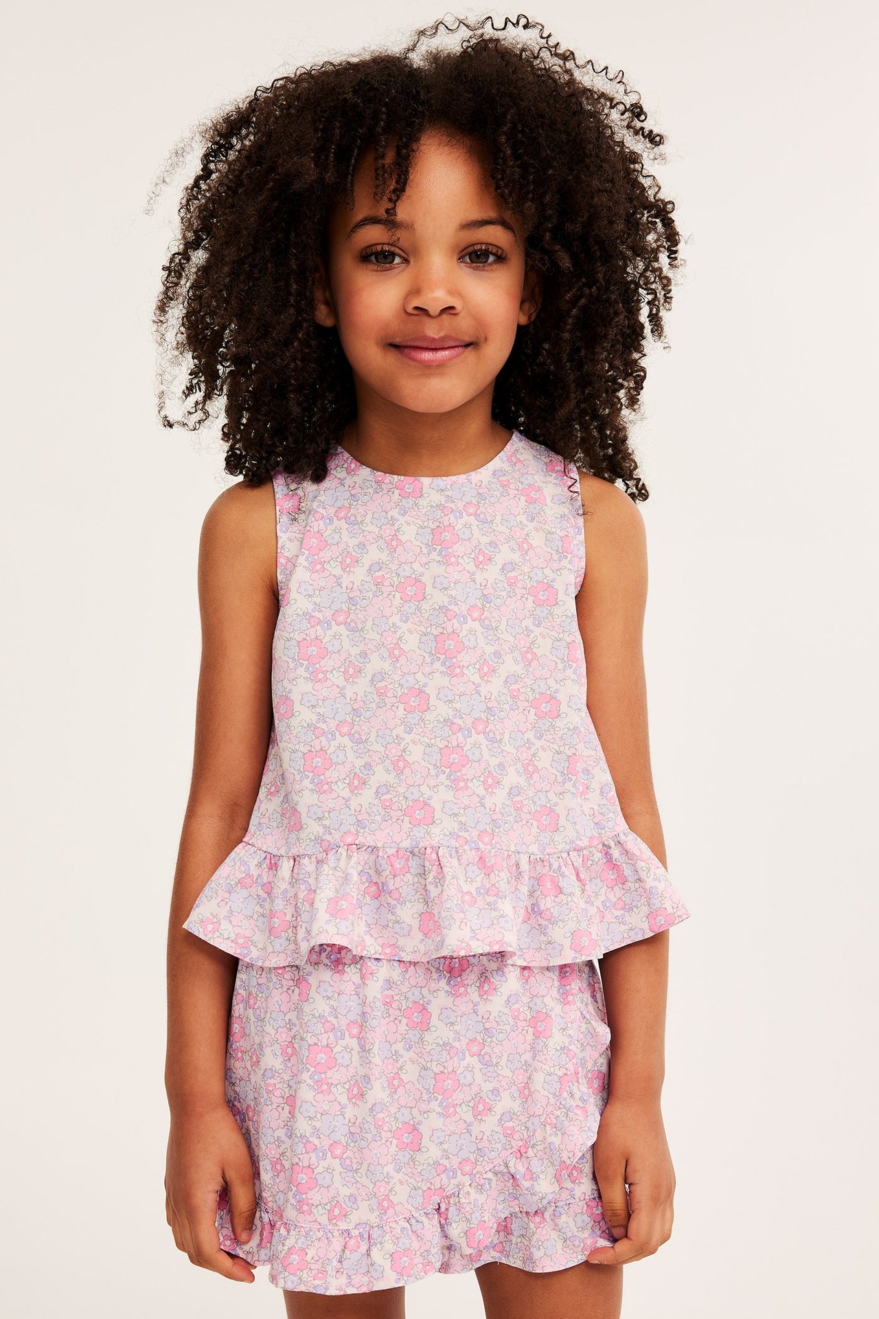 Framsida av ett barn i en rosa blommig viskoslinne med volangfåll och matchande volangkjol.