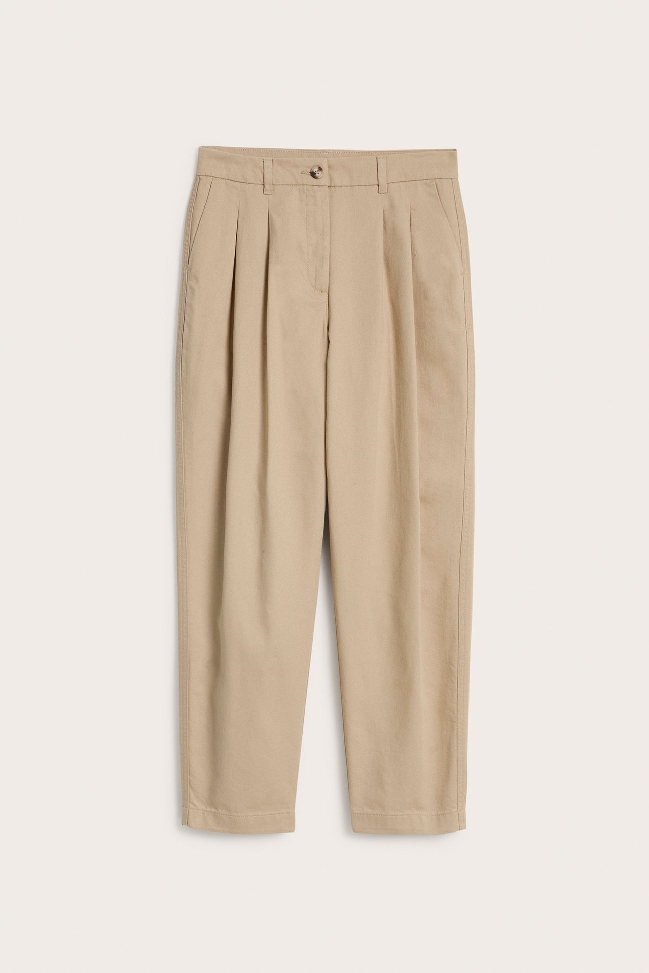 Widok z przodu beżowych bawełnianych spodni capri z zakładkami i zapięciem na guzik.