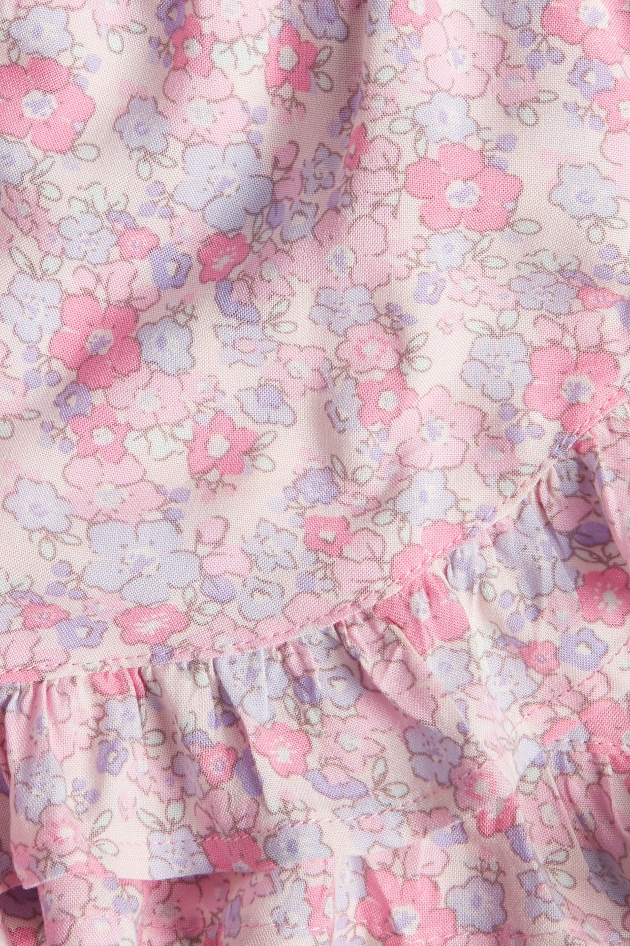 Zbliżenie różowej, kwiecistej spódnico-spodenek z wiskozy z falbanką.