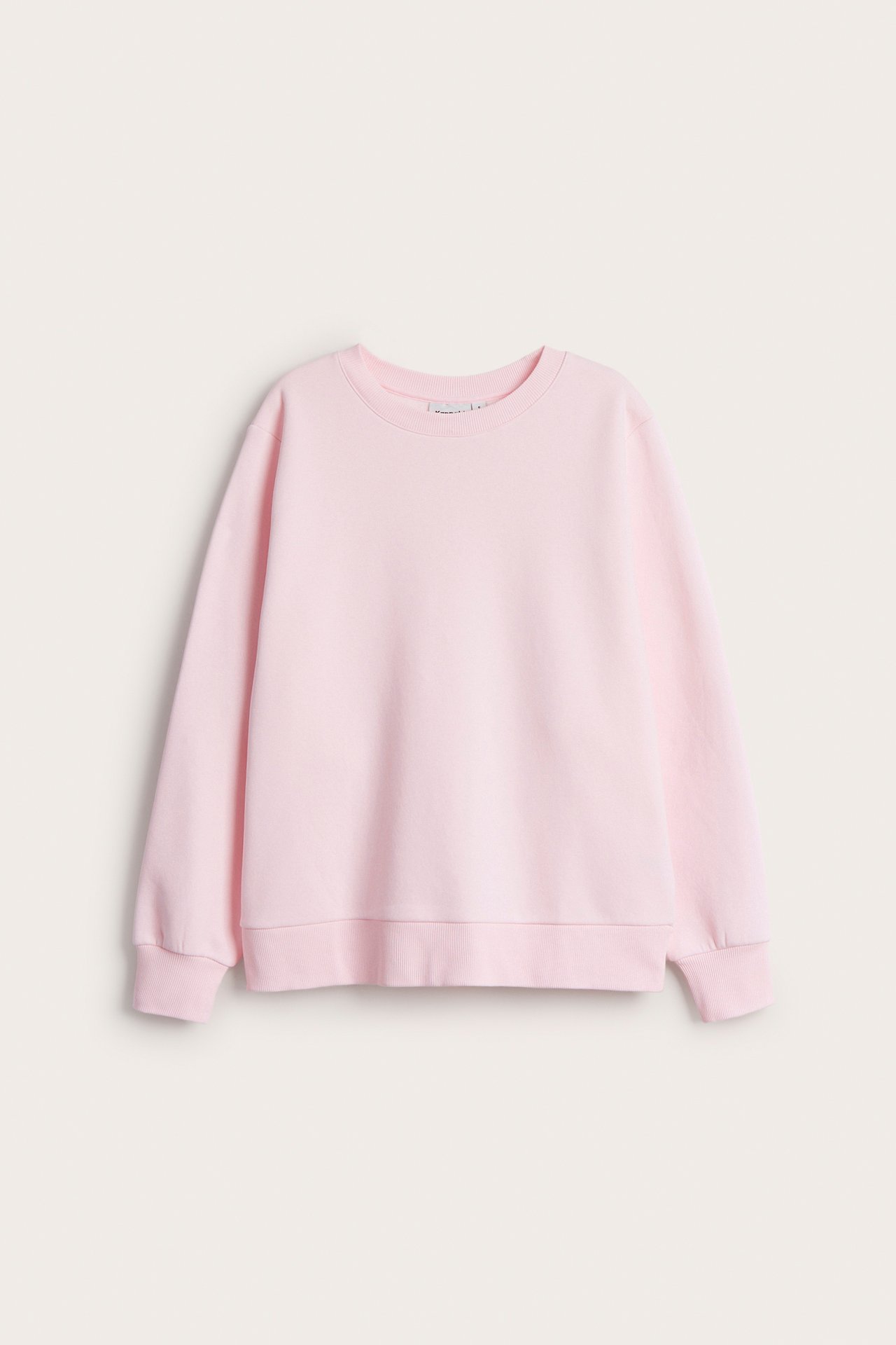 Framifrån, en ljusrosa sweatshirt med rund hals, långa ärmar, ribbade muddar och nederkant.
