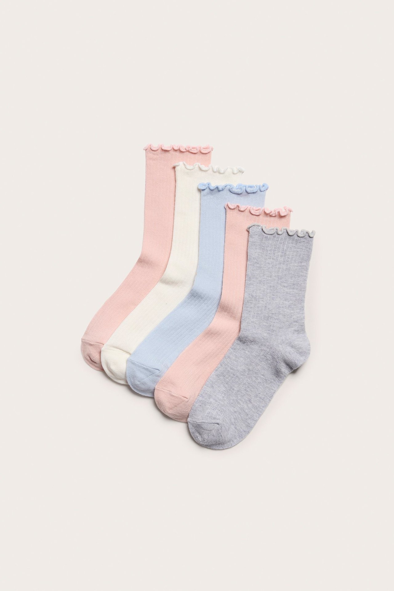 Ylhäältä näkymä viidestä ribbineuleisesta sukasta, joissa on röyhelöreunat; vaaleanpunainen, luonnonvalkoinen, vaaleansininen, vaaleanharmaa.