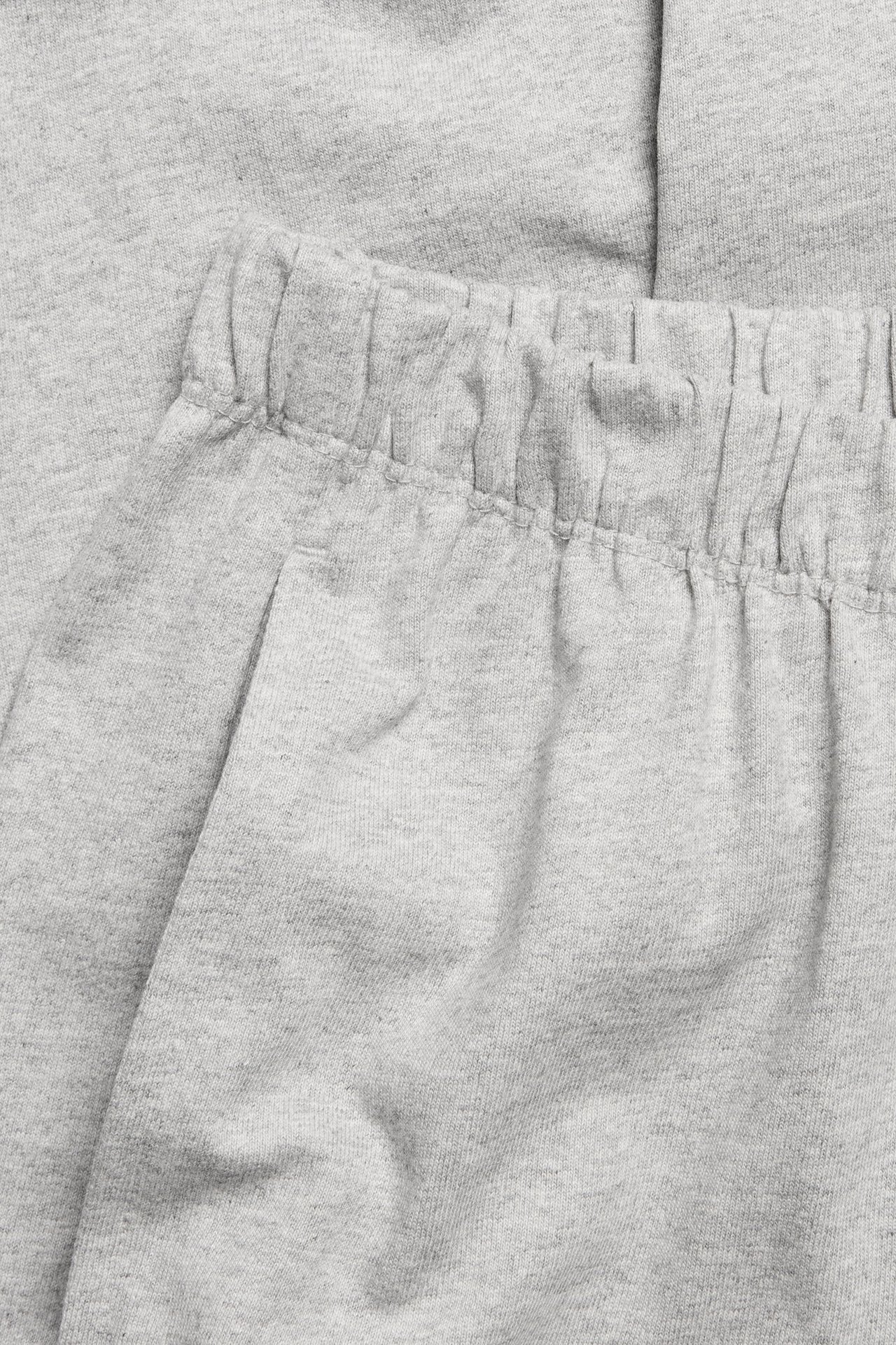 Zbliżenie na szare melanżowe proste bawełniane joggery z elastycznym pasem i boczną kieszenią.