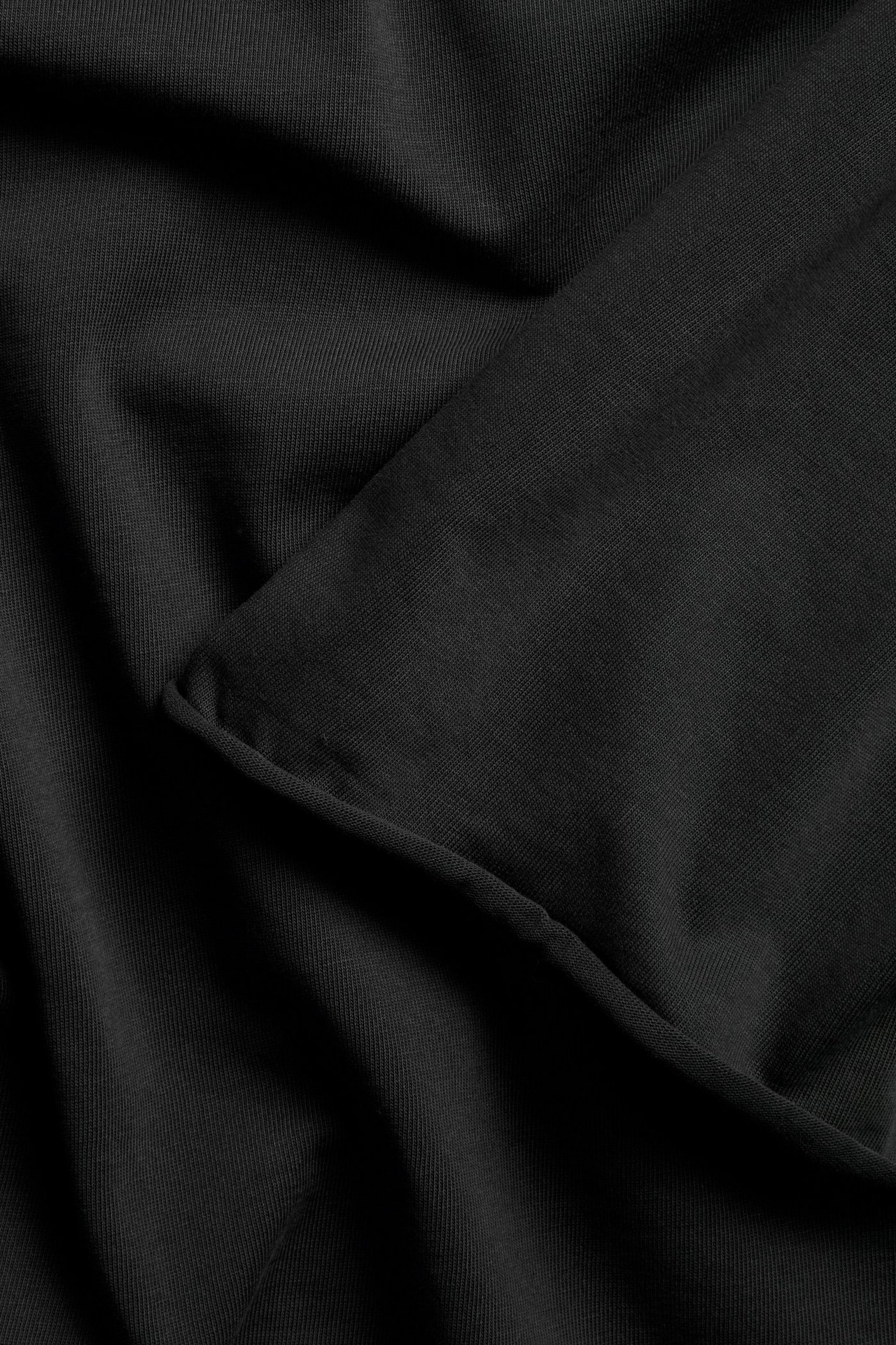 Czarna koszulka z grubszej dzianiny, wykończenie surowe, damska, widok z przodu.