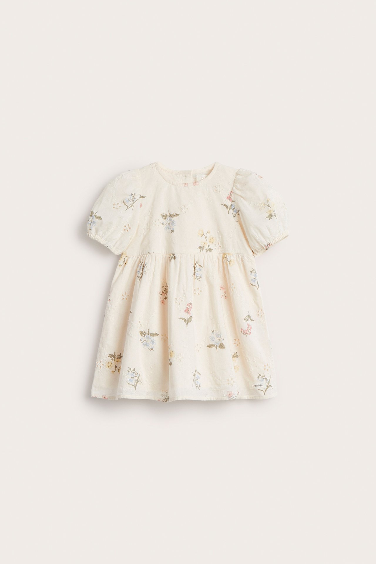 Edestä: Lasten luonnonvalkoinen broderie anglaise -mekko kukkakuviolla ja lyhyillä pussihihoilla.