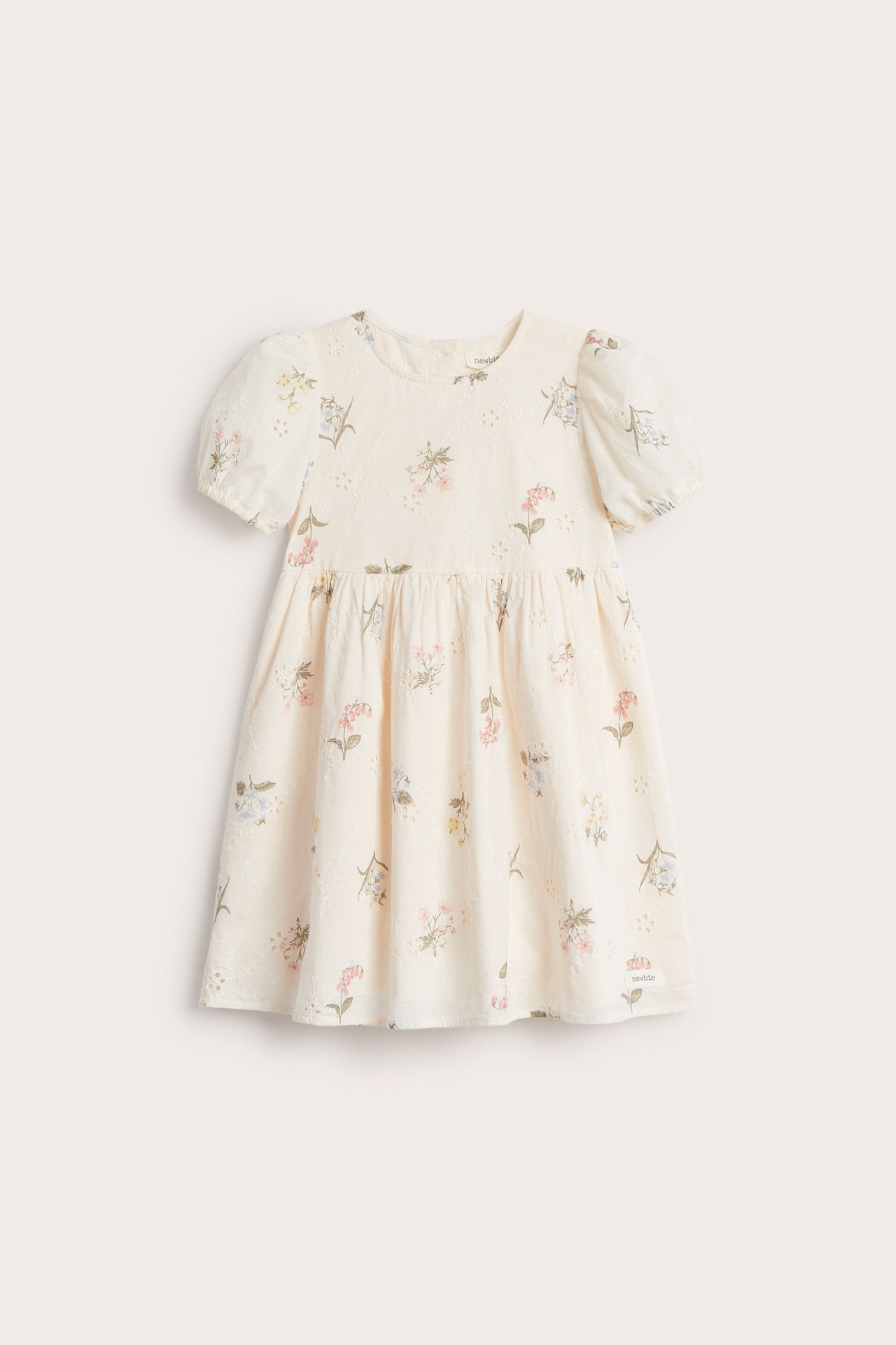 Edestä näkymä luonnonvalkoisesta lasten mekosta, jossa broderie anglaise ja pieniä kukkakuvioita, puffihihoilla.