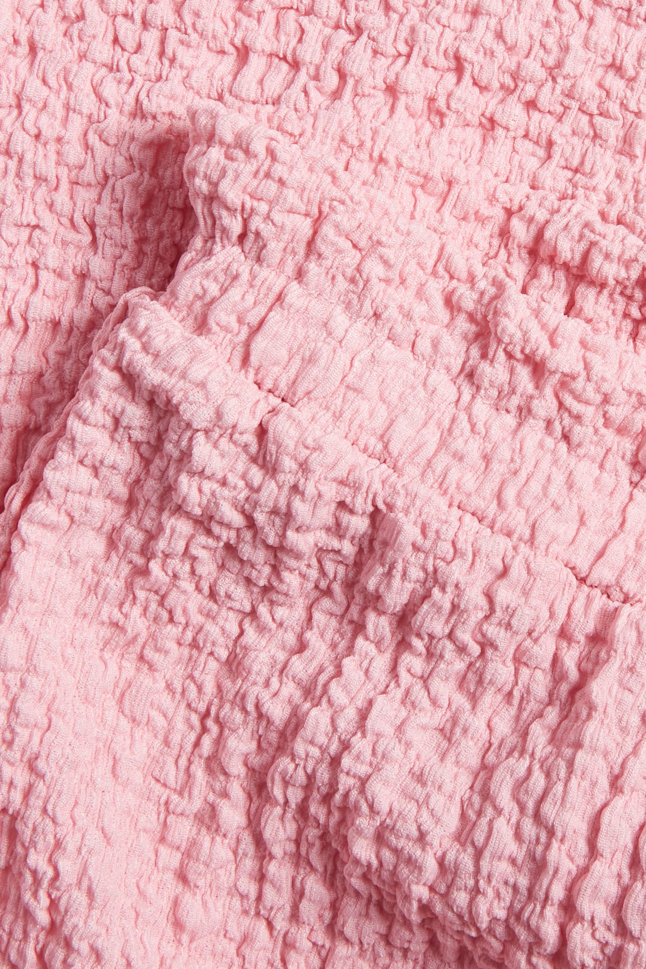 Närbild av rosa strukturerat jerseymaterial, del av culottebyxor.