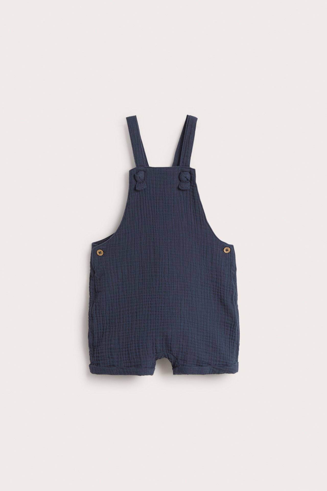 Frontvisning av mørkeblå vevde bomulls-baby-seleshorts med justerbare knyttede stropper og sideknapper.