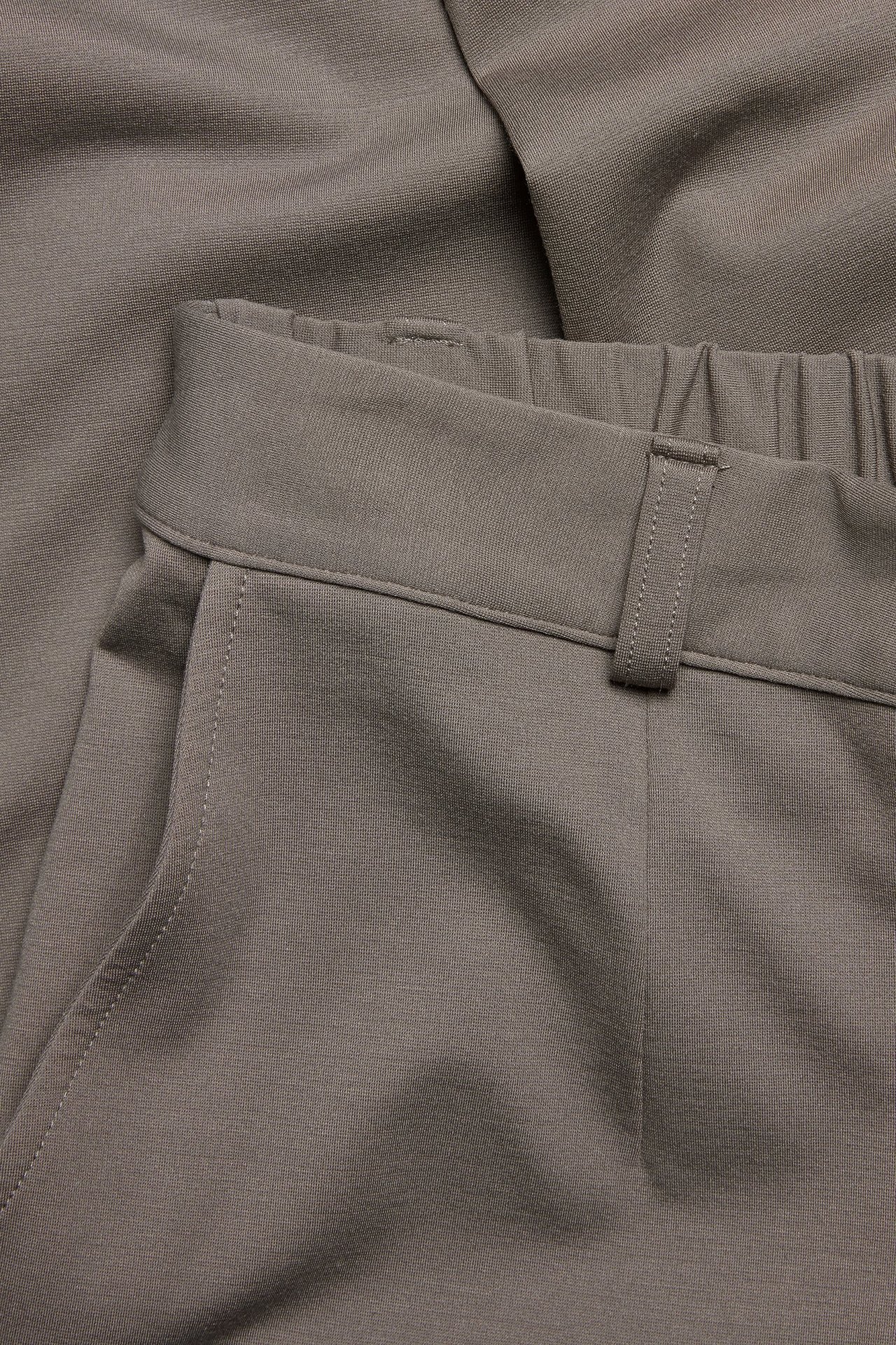 Zbliżenie brązowych spodni garniturowych Punto Jersey z elastyczną talią, szlufkami i kieszenią.