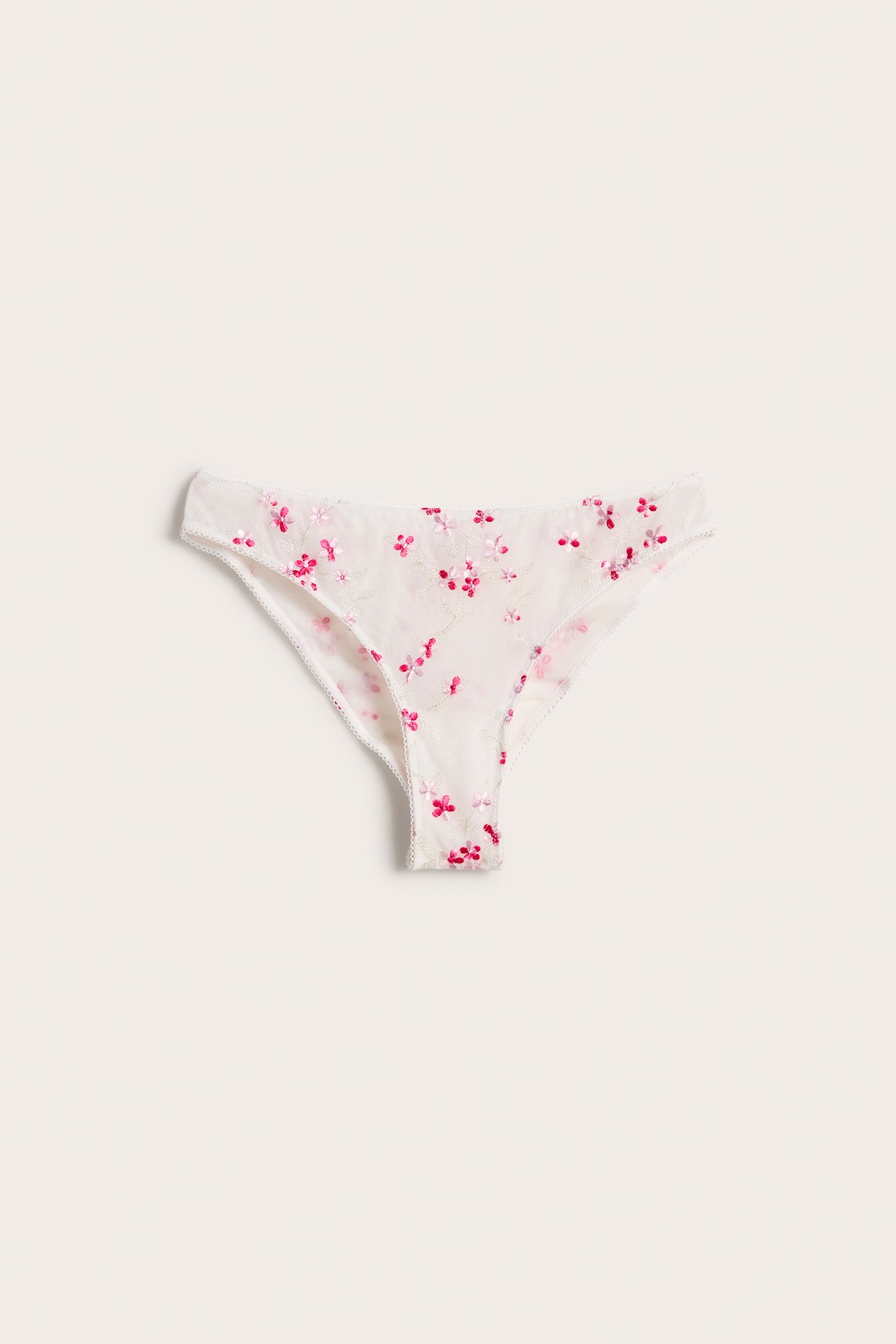 Frontvy av offwhite skira lågmidjade brazilian trosor med rosa blomsterbrodyr.