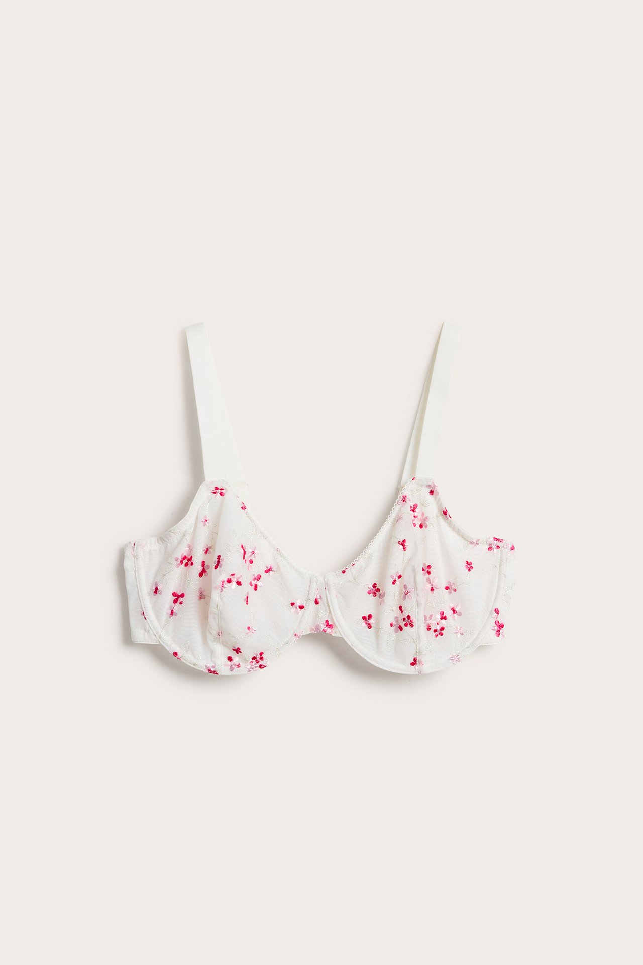 Frontvisning av en offwhite uvattert bøyle-BH med rosa blomsterbroderi og justerbare stropper.