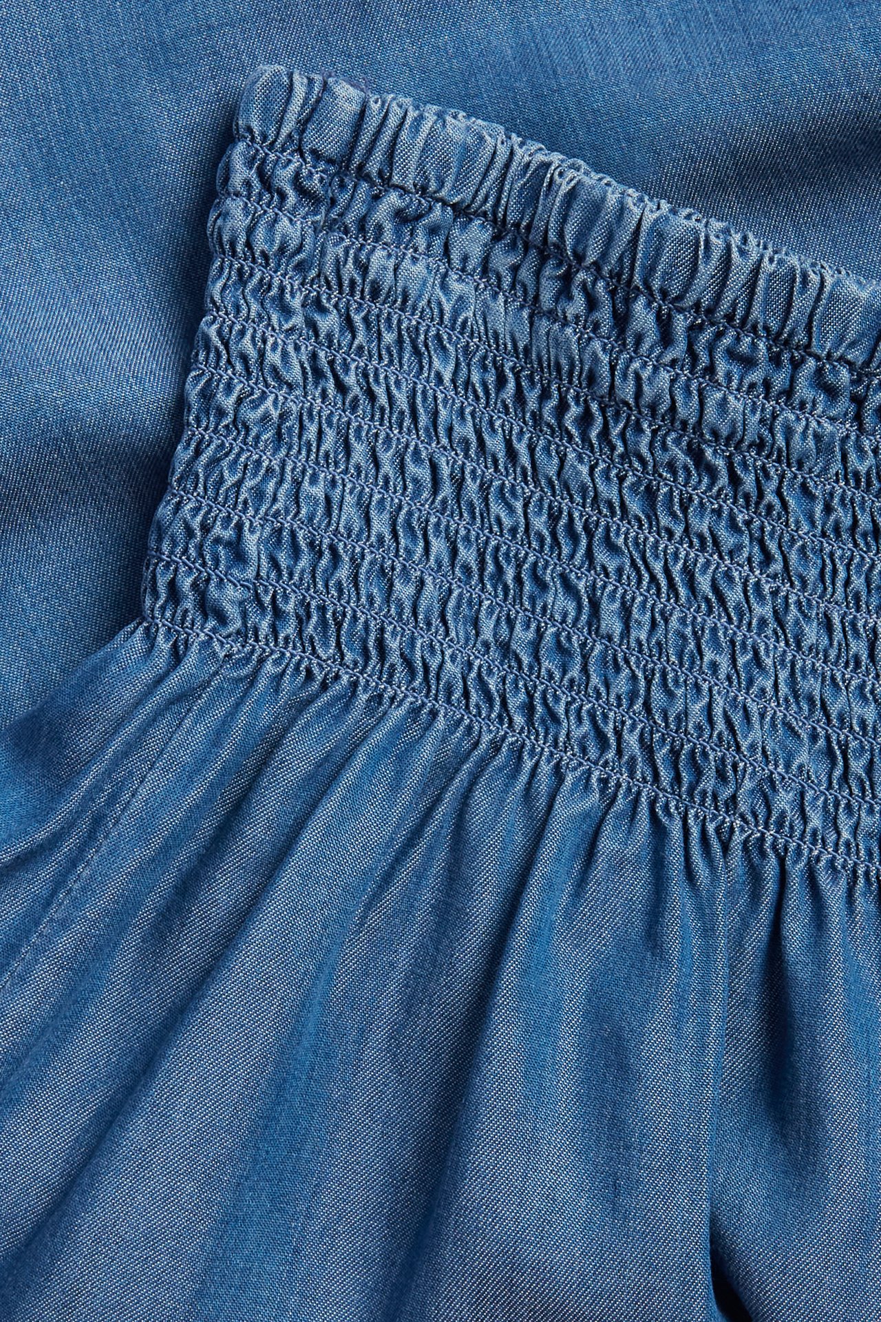 Nærbilde av blå Lyocell-shorts med smock i midjen.