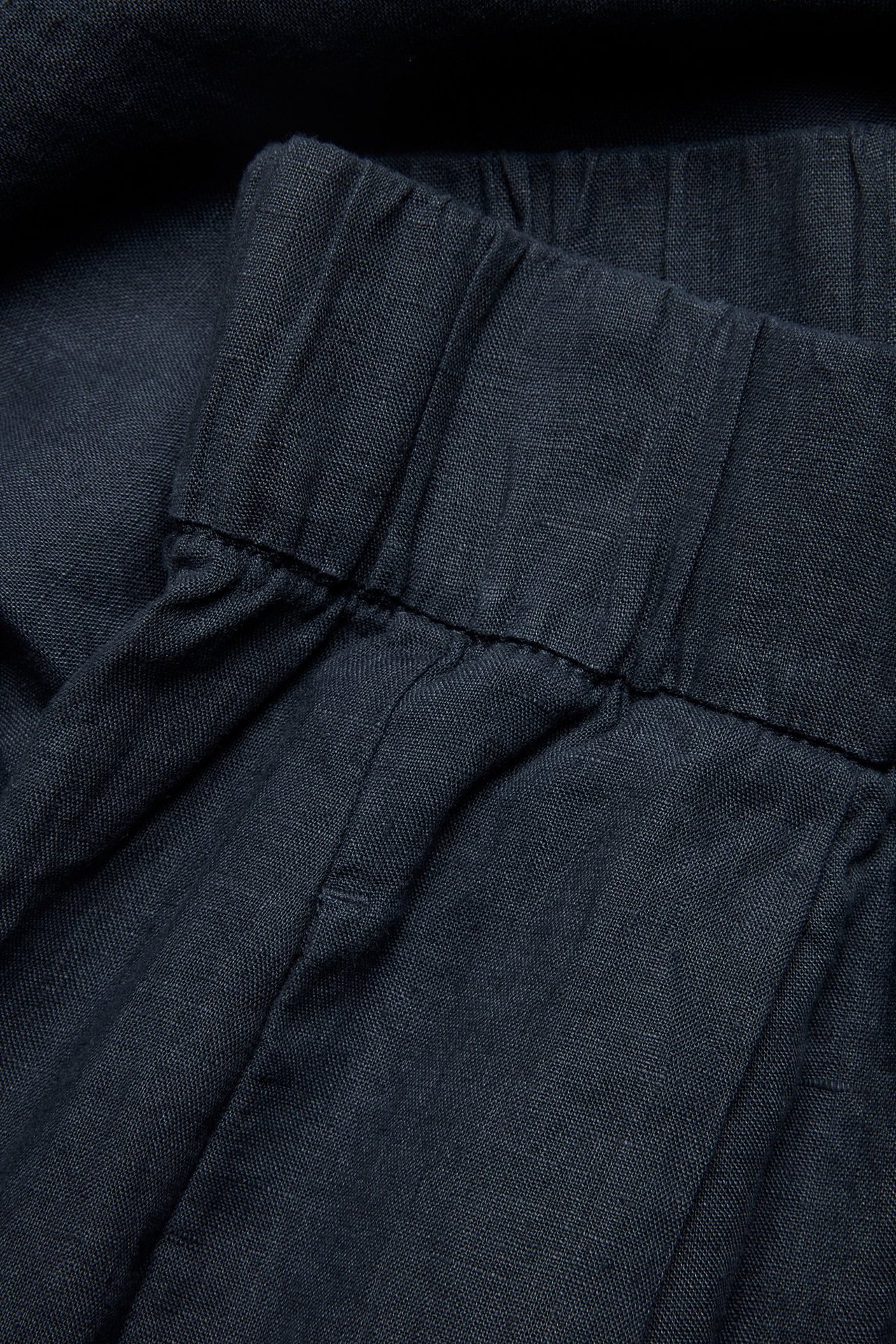 Zbliżenie na granatowe lniane szorty z elastyczną talią.